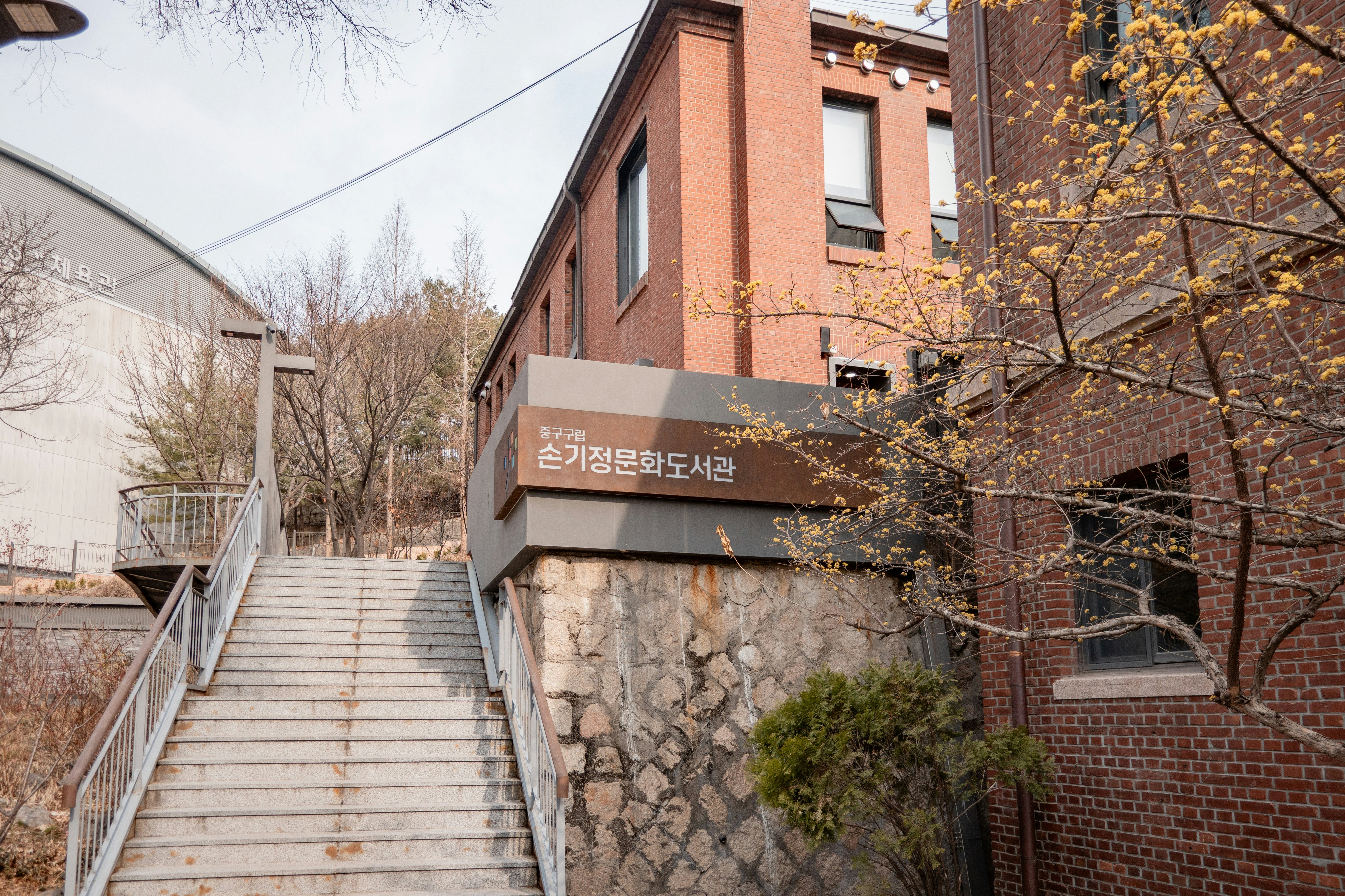 Stone stairs lead to a brick building with a sign.