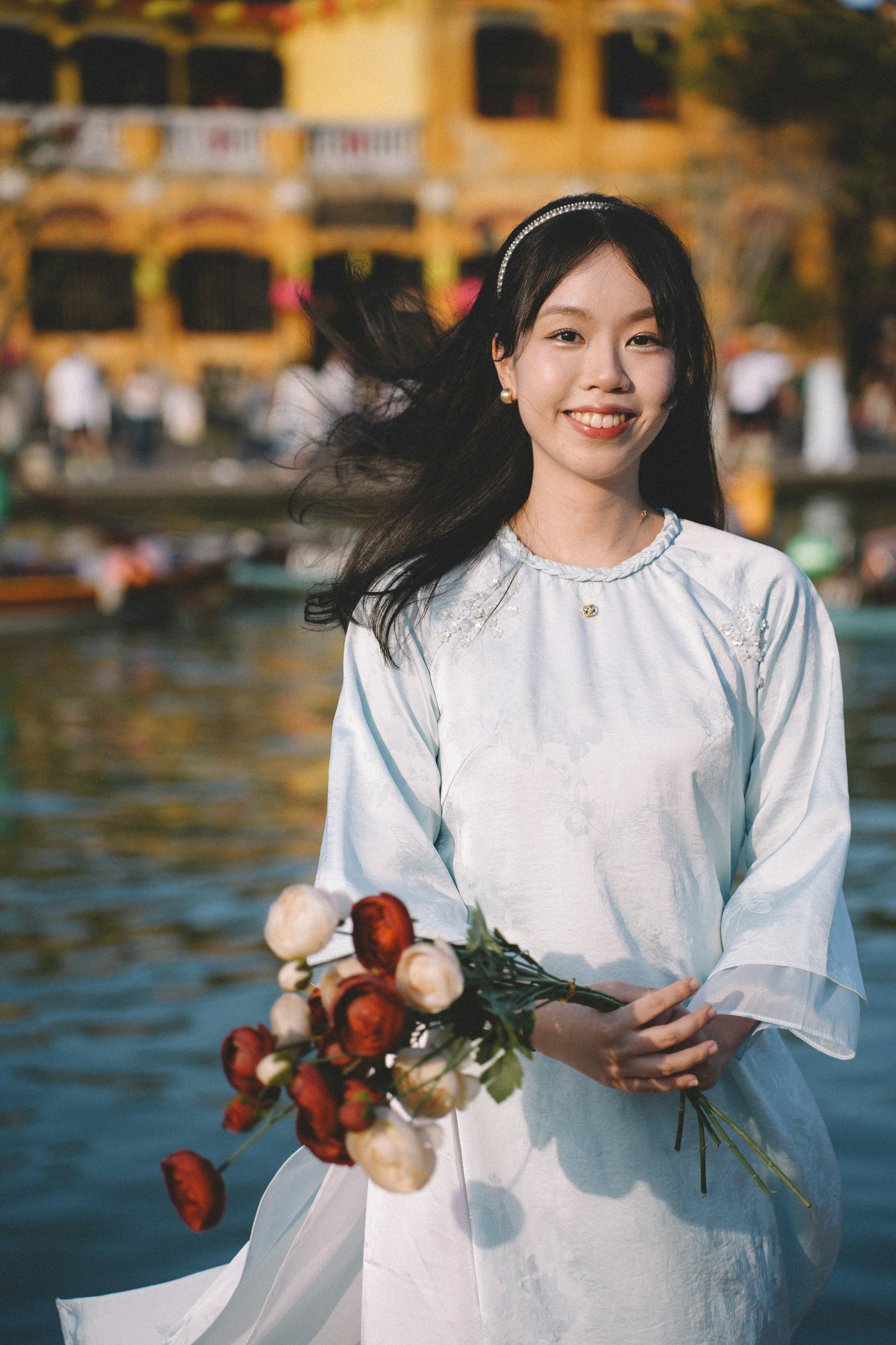 A smiling young woman holds a bouquet of roses.