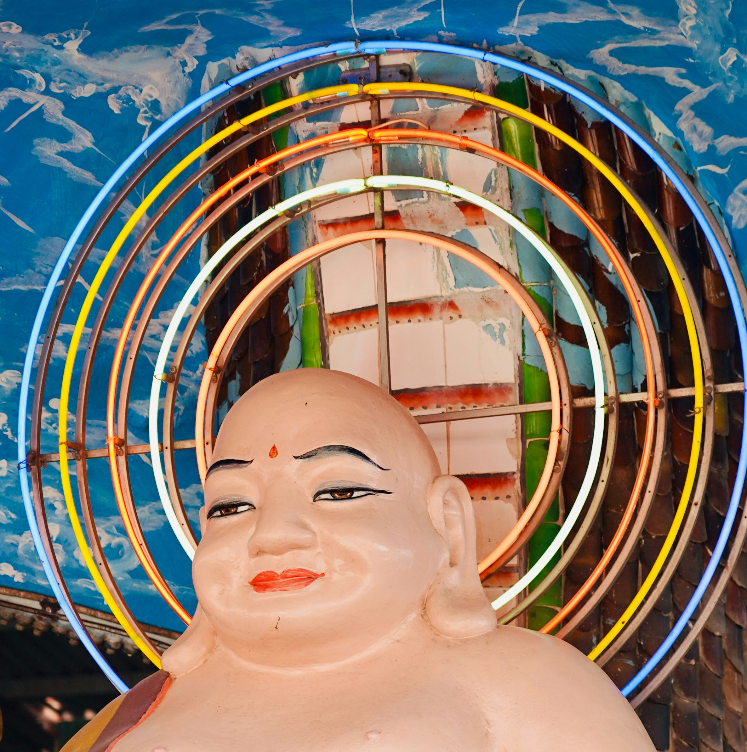 Una estatua de un Buda sonriente con anillos de neón