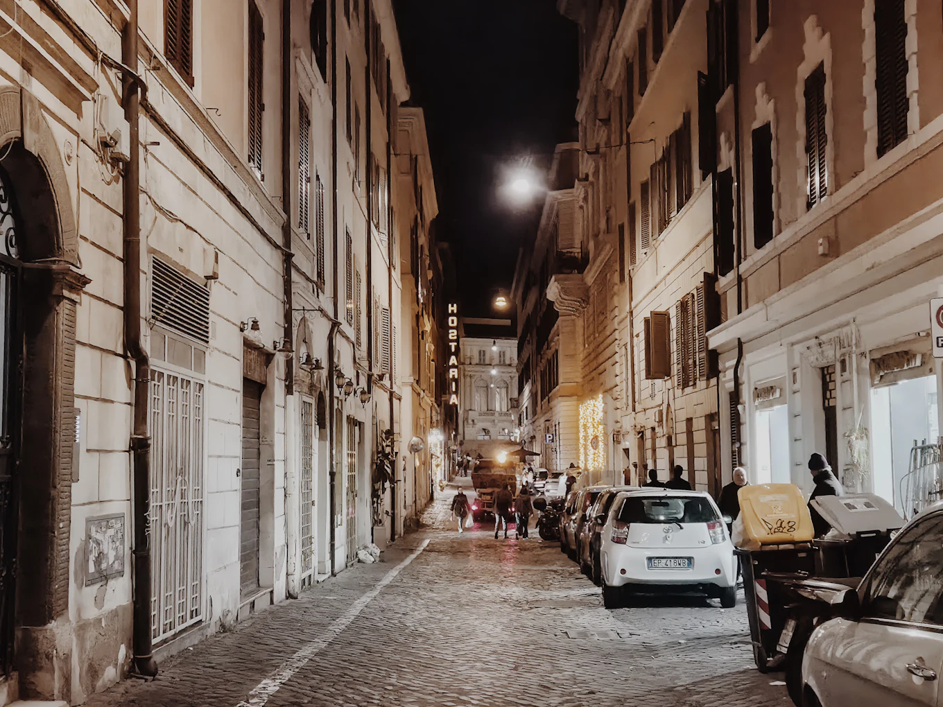 The street at night, the lamps on over the cobbles