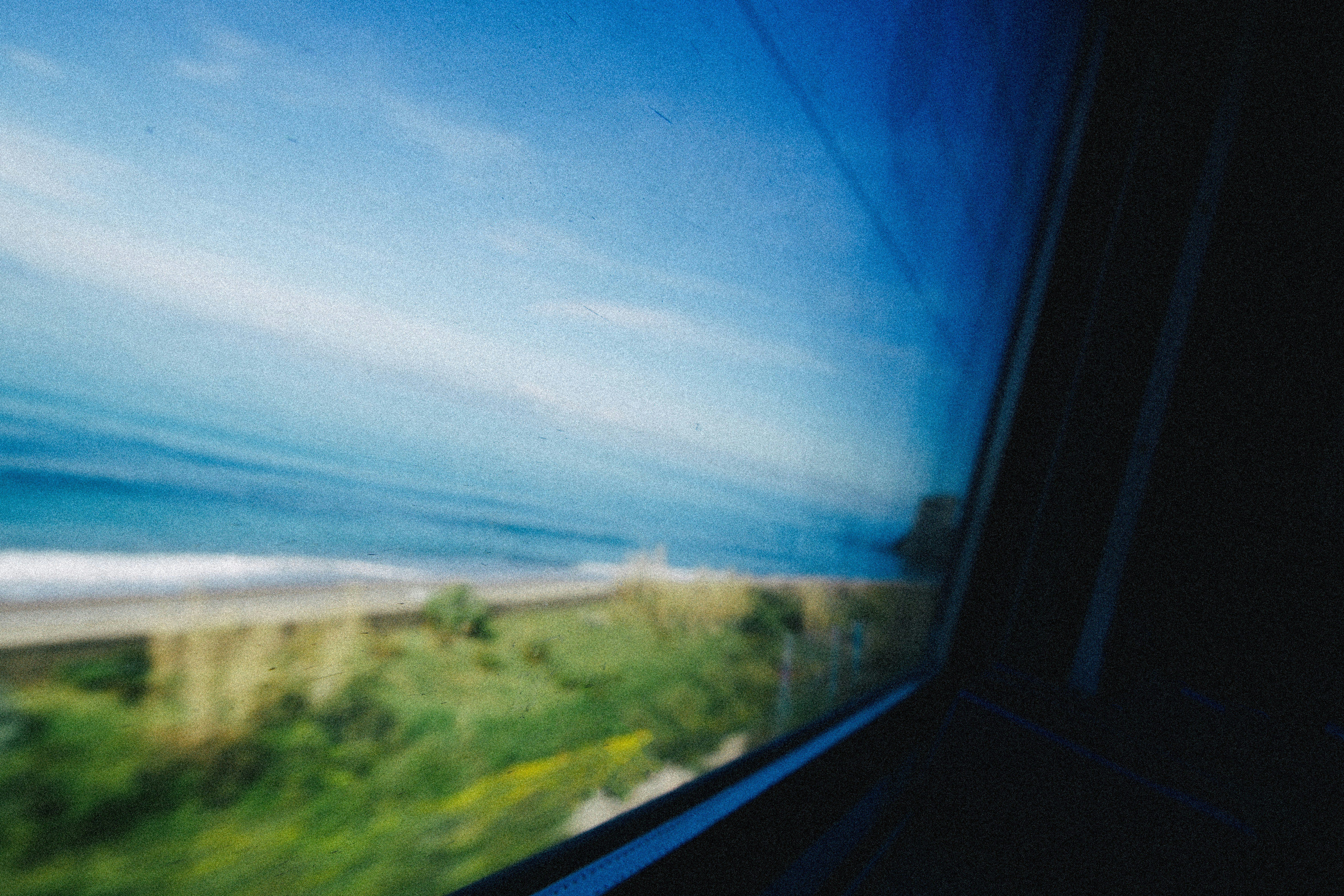 View of the ocean and coastline from a moving train.