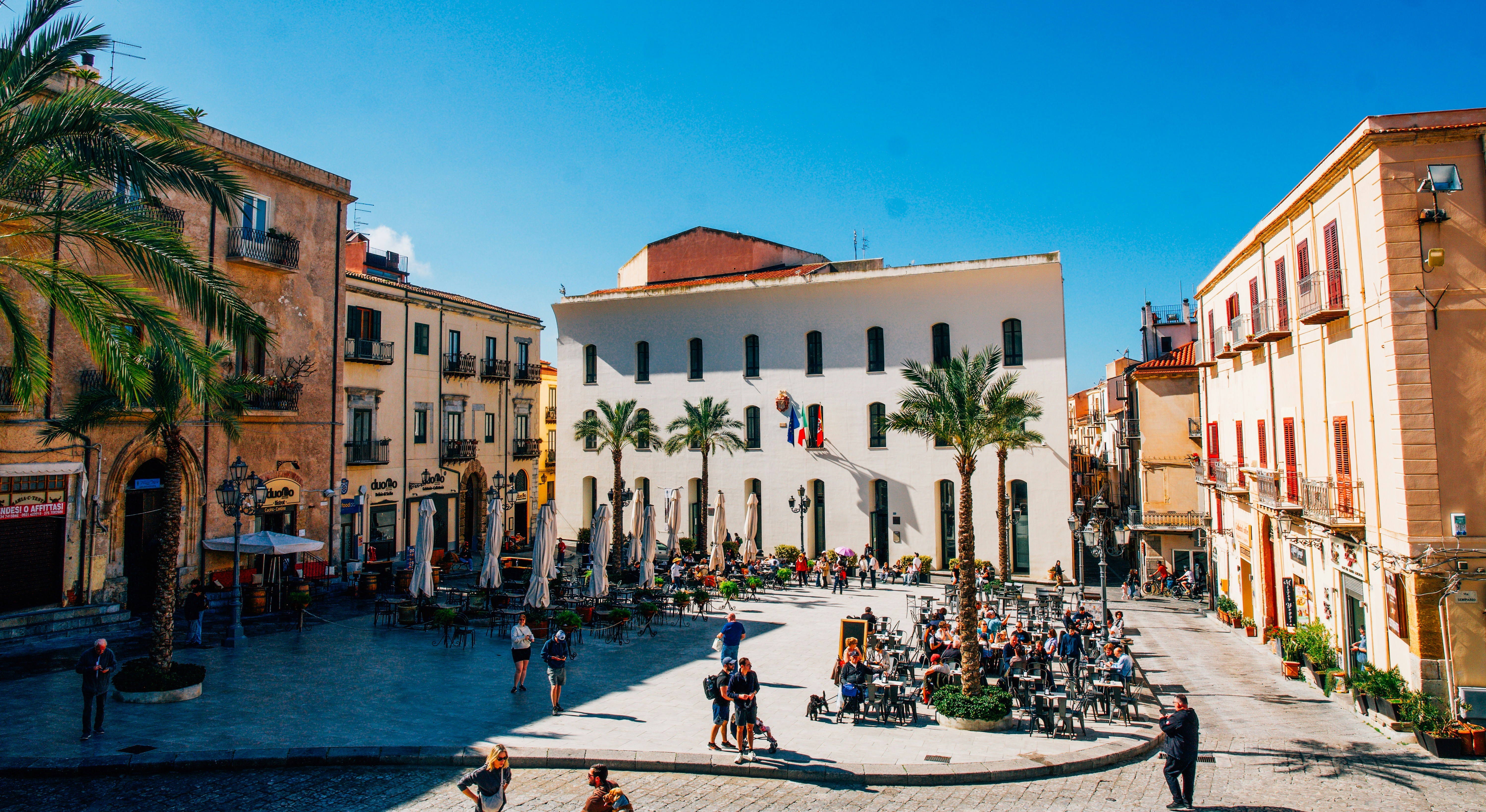 People sitting at tables in a sunny european town square.