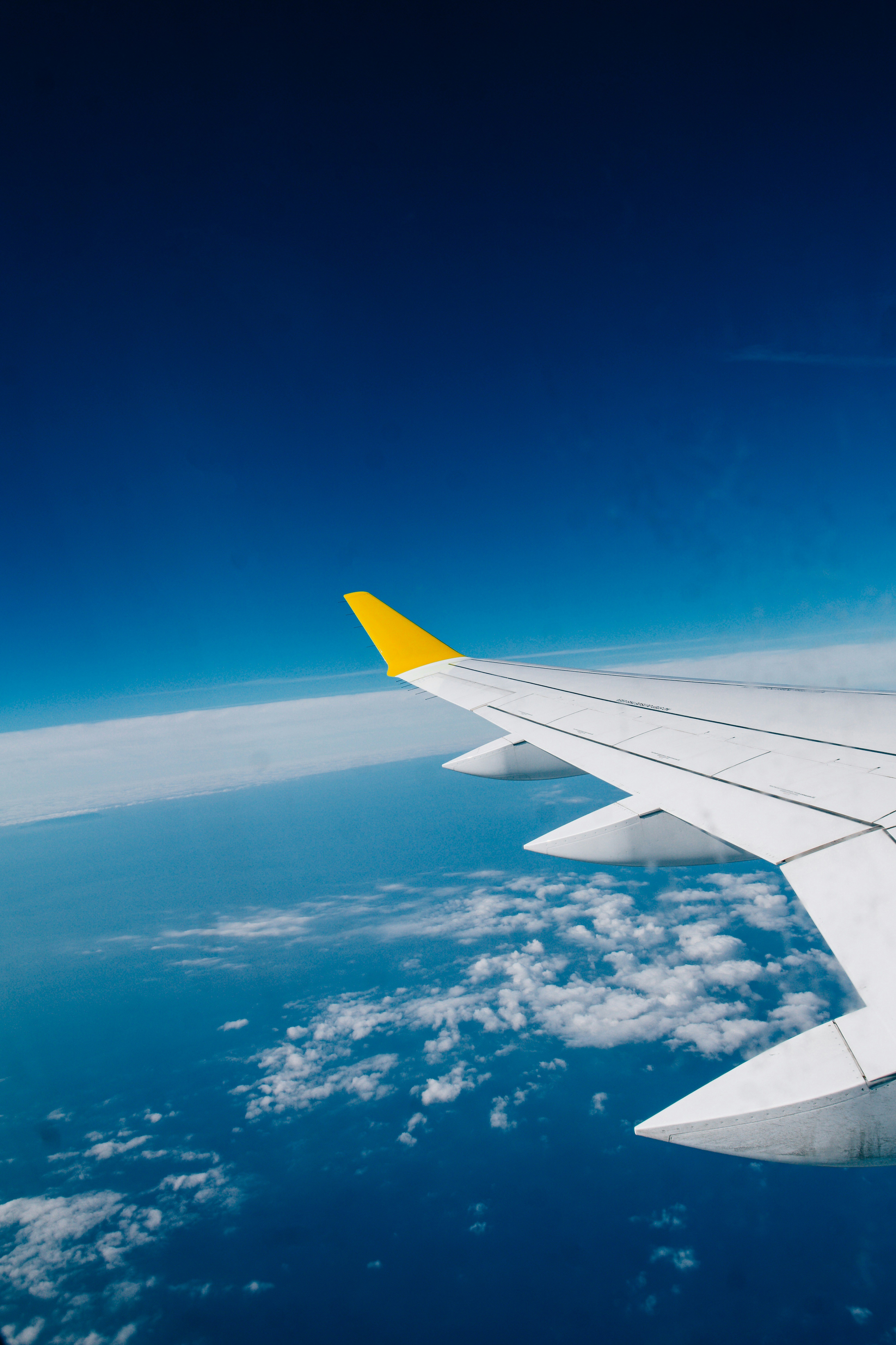 Airplane wing flying over clouds and ocean