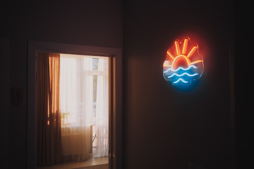Neon sun and waves sign on wall