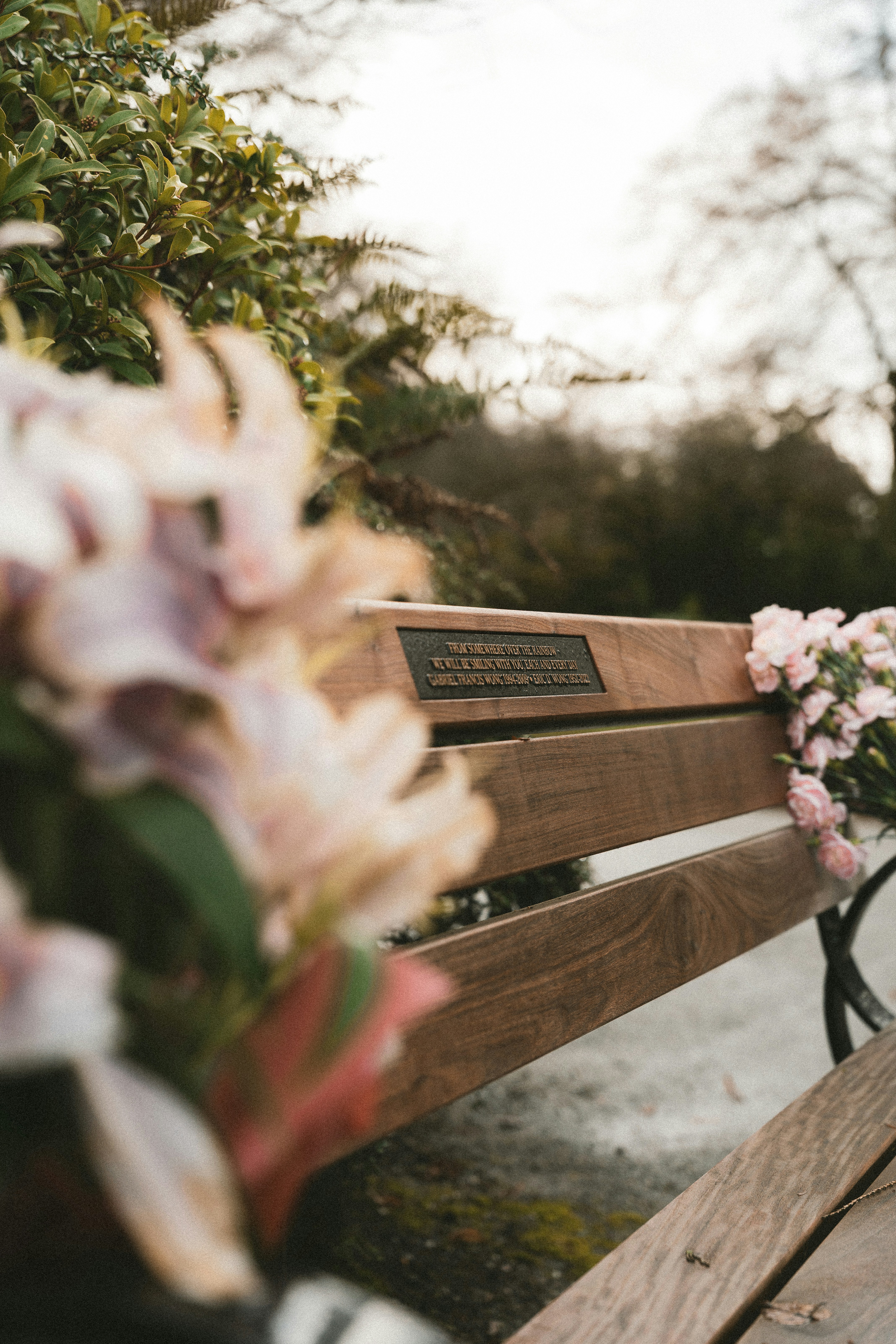 Wooden park bench with flowers and memorial plaque