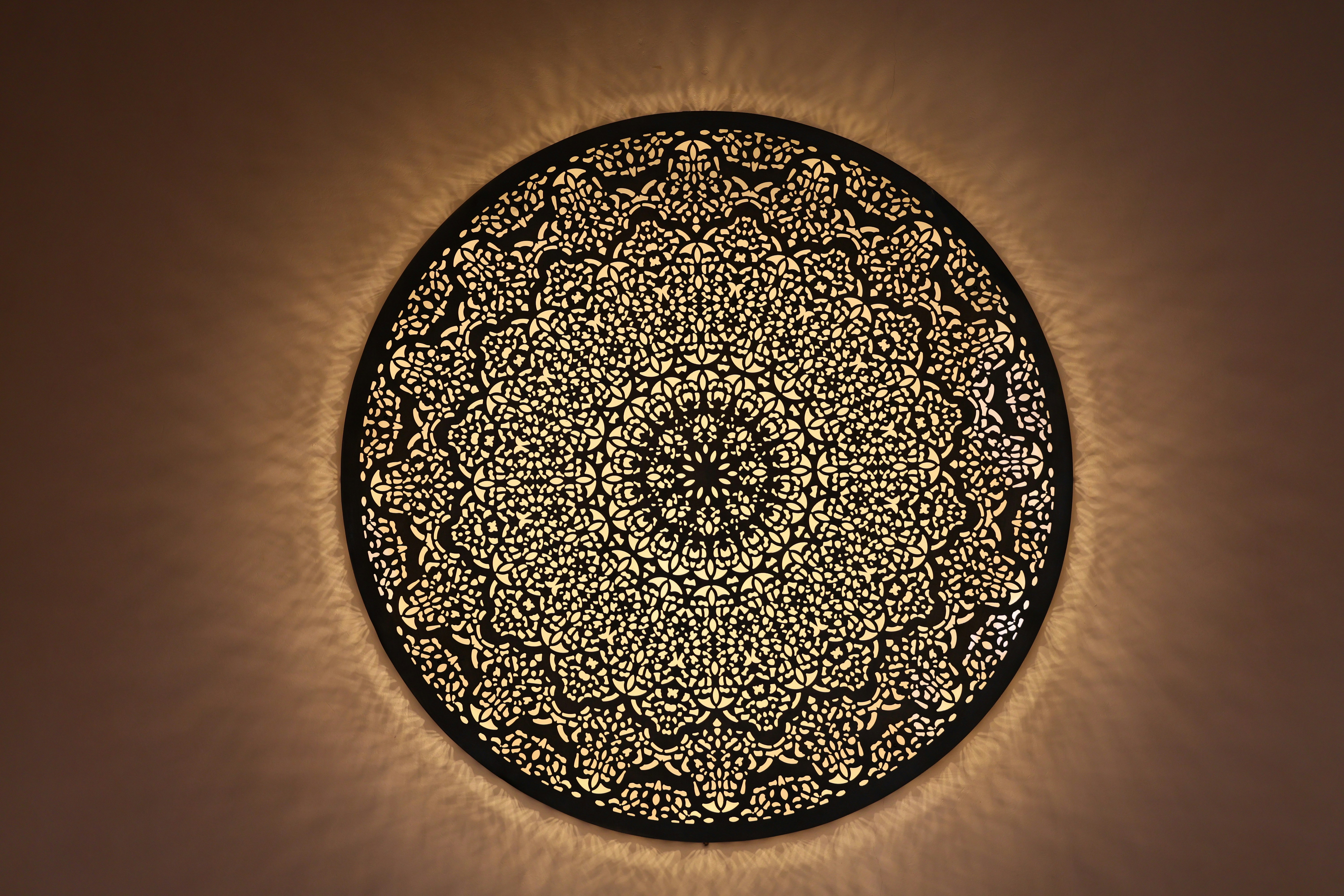 Intricate circular moroccan lantern with glowing light.