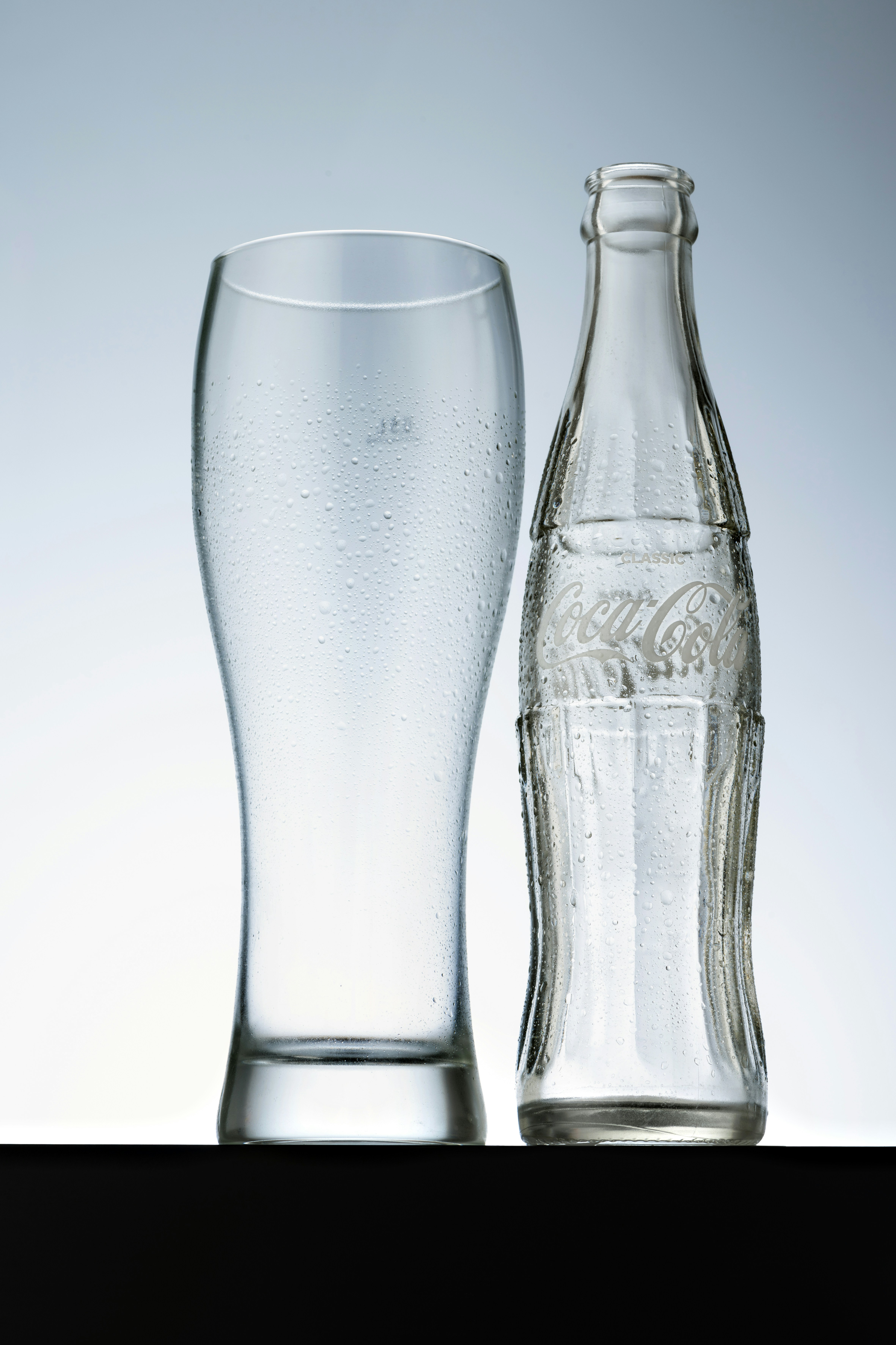 Leere Glas- und Coca-Cola-Flasche mit Kondenswasser