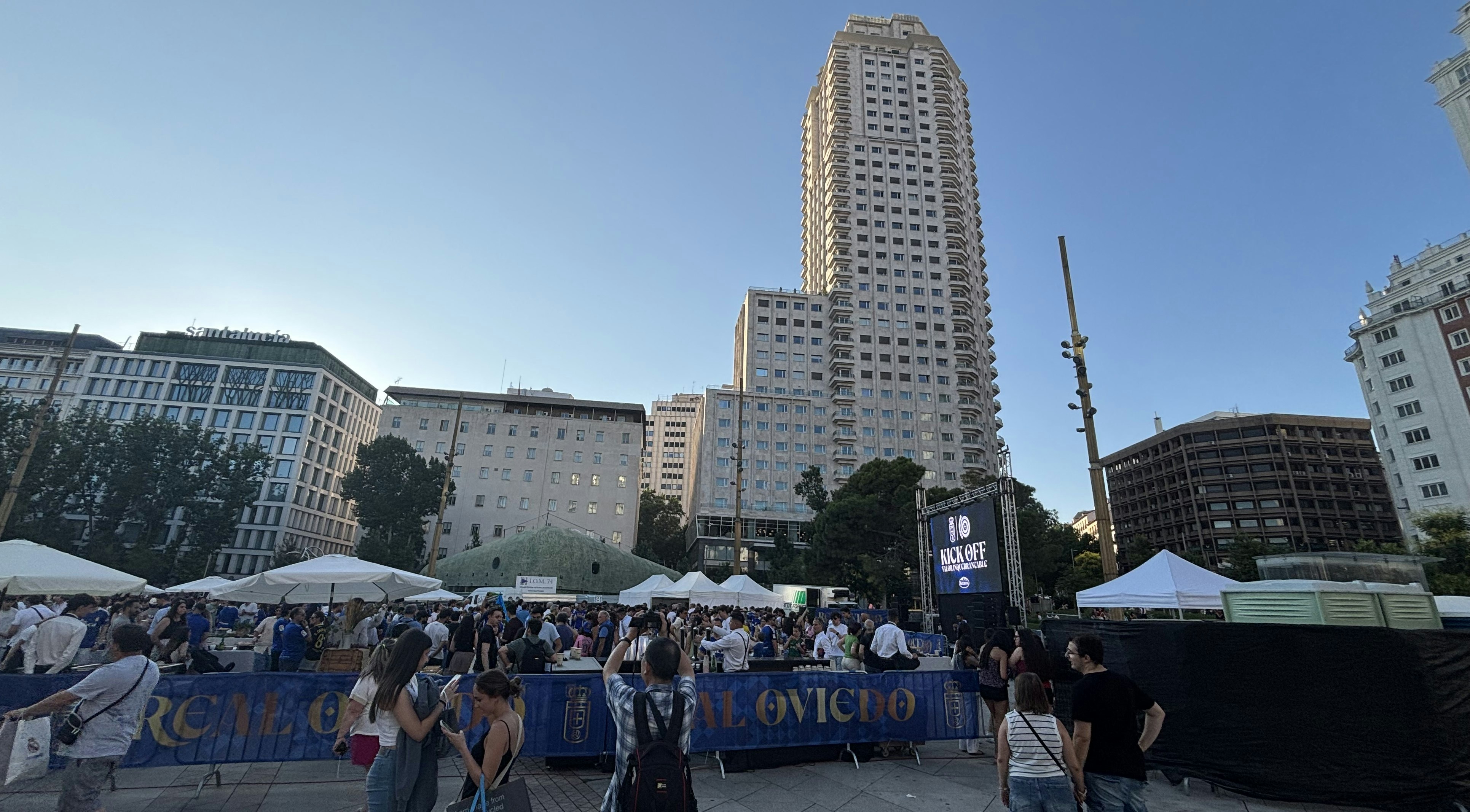 People gathered in outdoor plaza with tall building background.