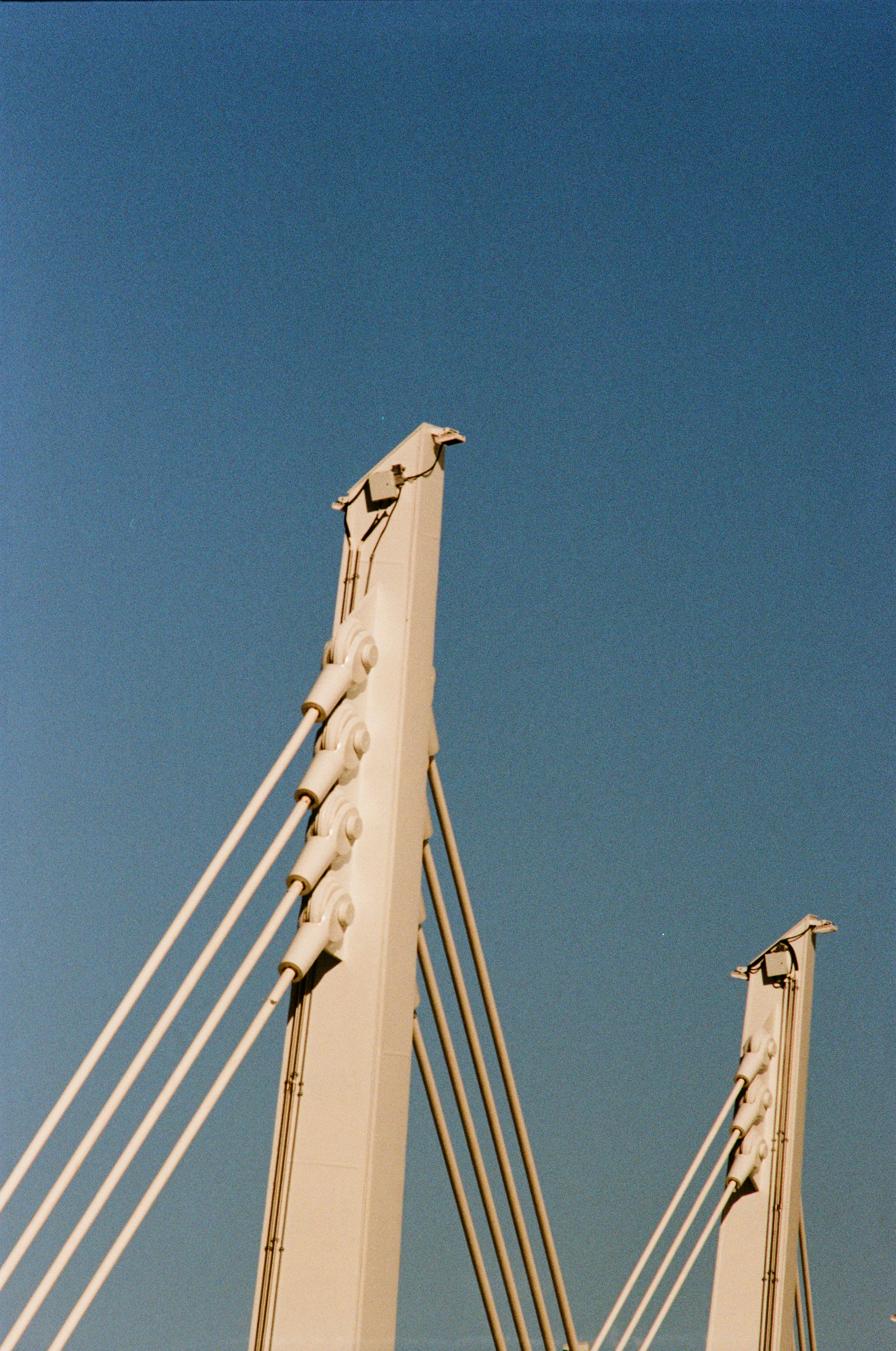 Two white bridge towers against a clear blue sky.