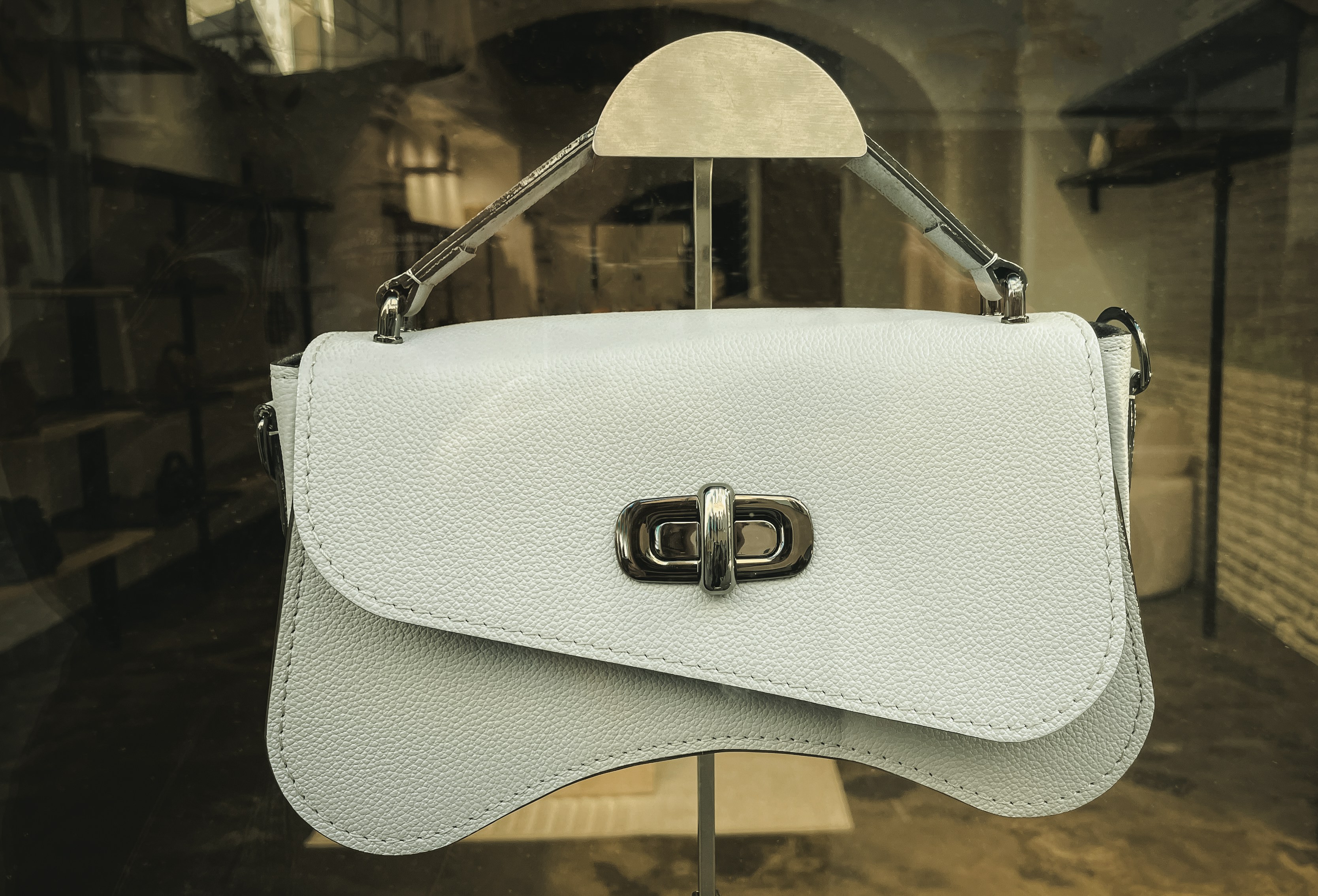 A white leather handbag with a silver clasp