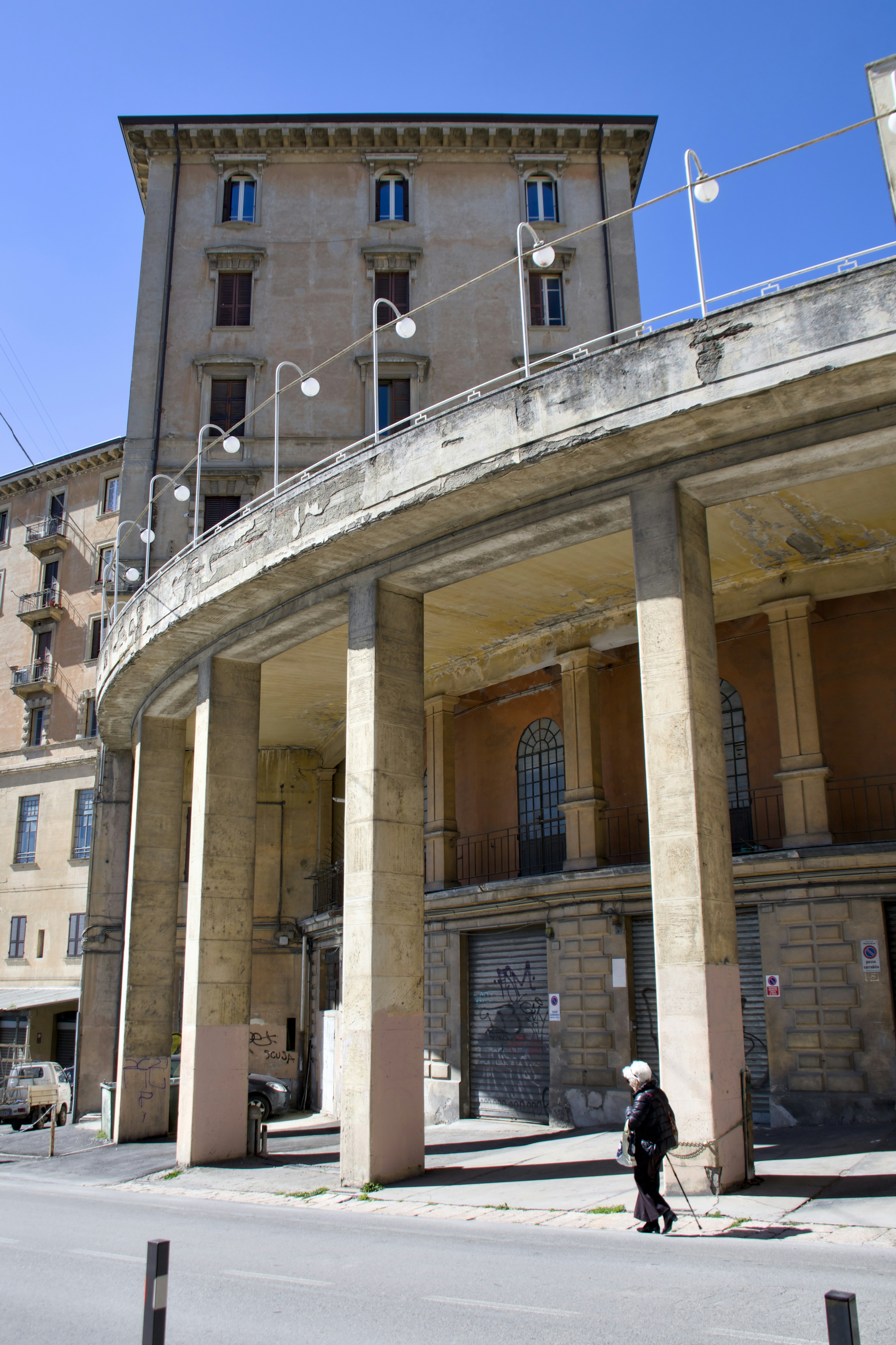 Woman walking past concrete columns under building