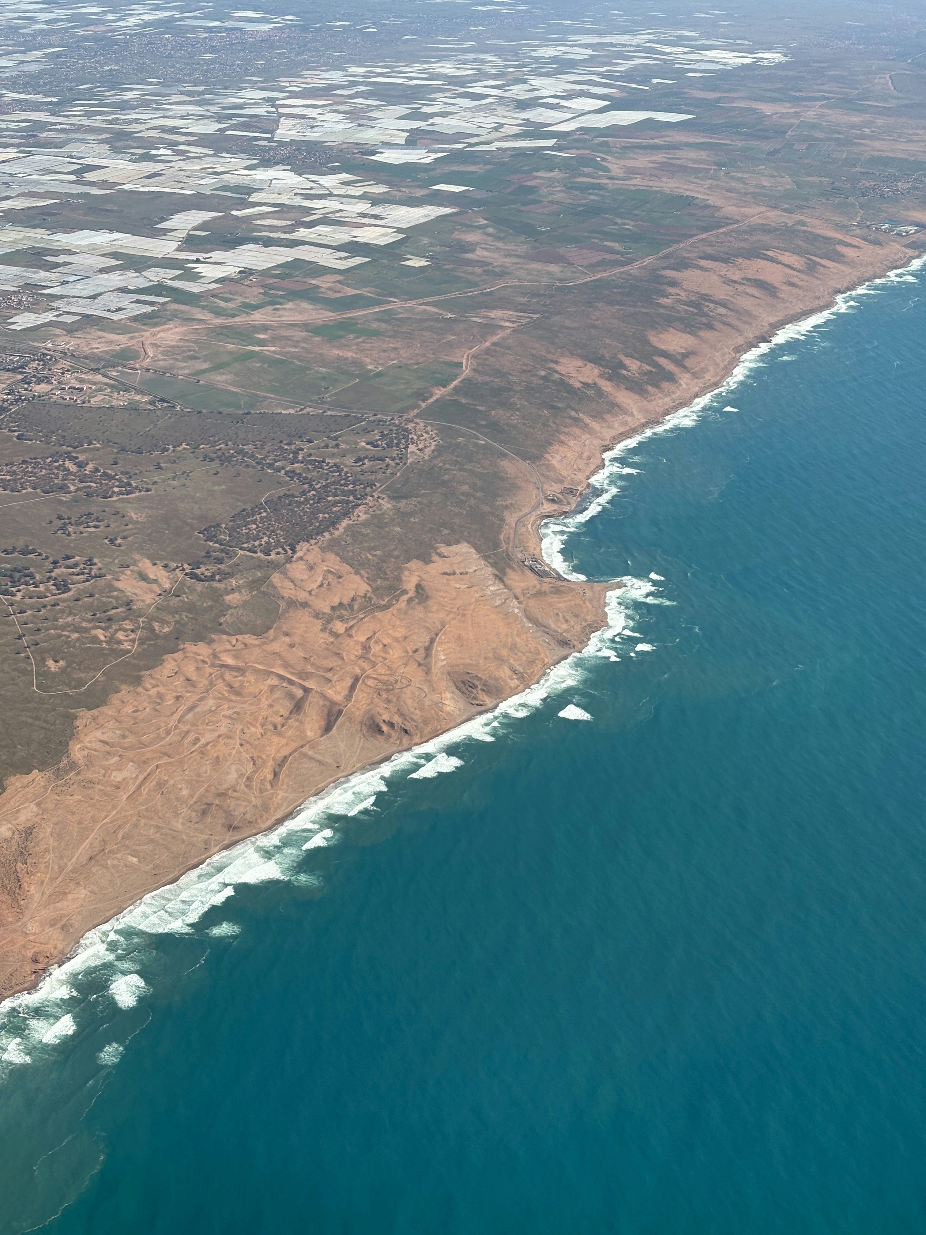Aerial view of a coastline with waves crashing on shore.