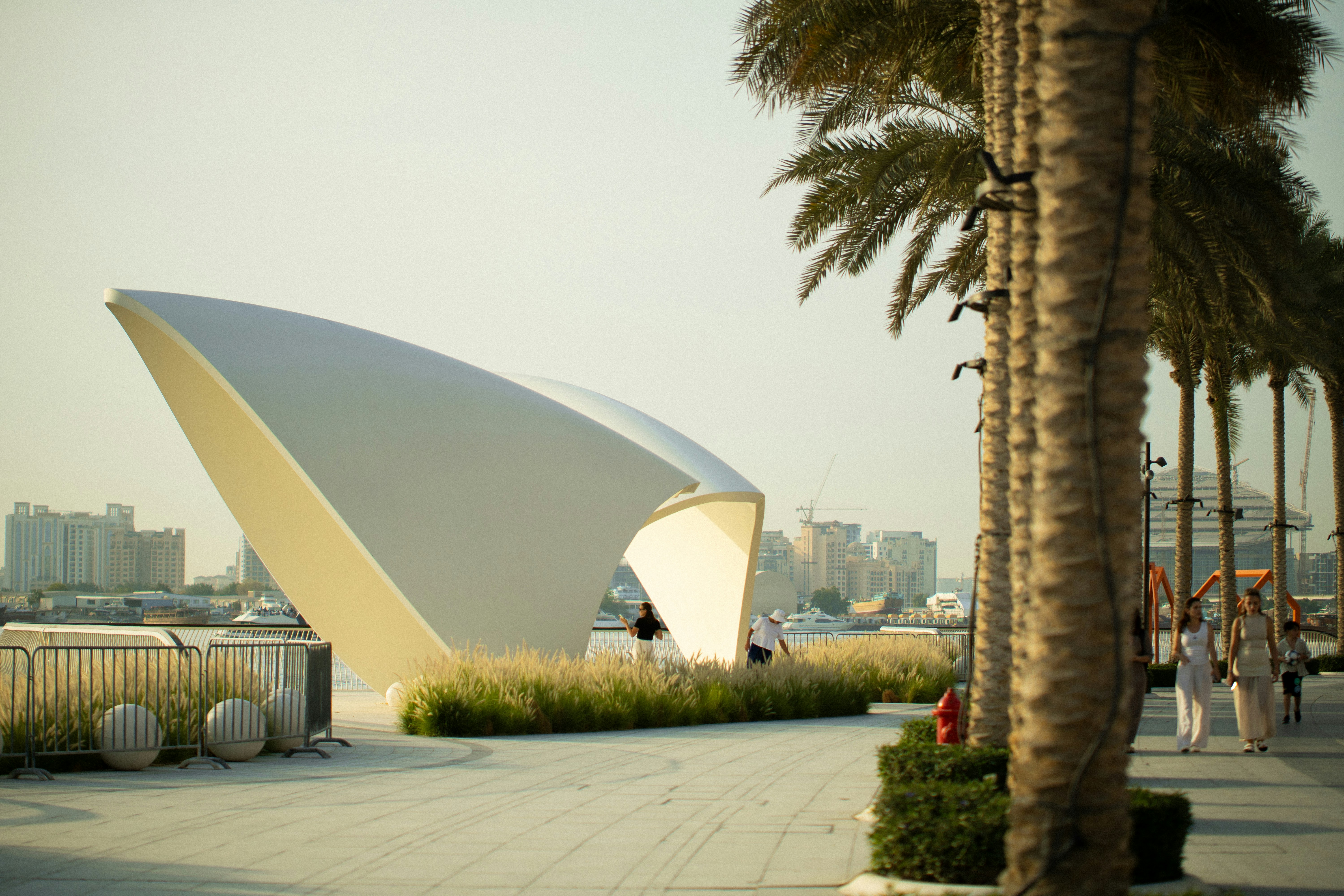 Modern white structure with palm trees and people walking