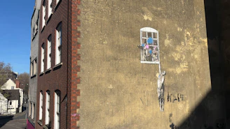 Street art of a figure hanging from window