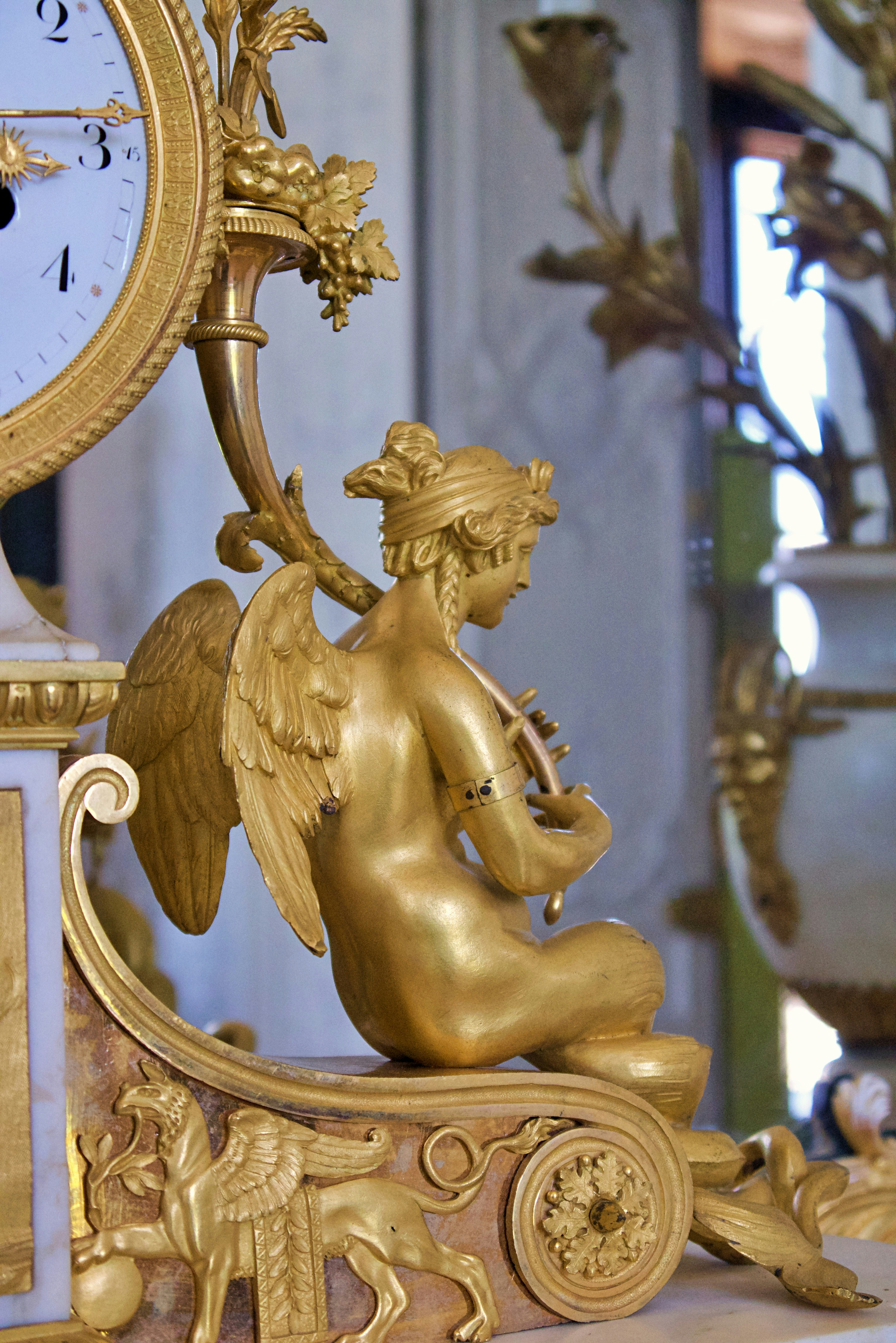 Querubim dourado toca lira em relógio antigo ornamentado