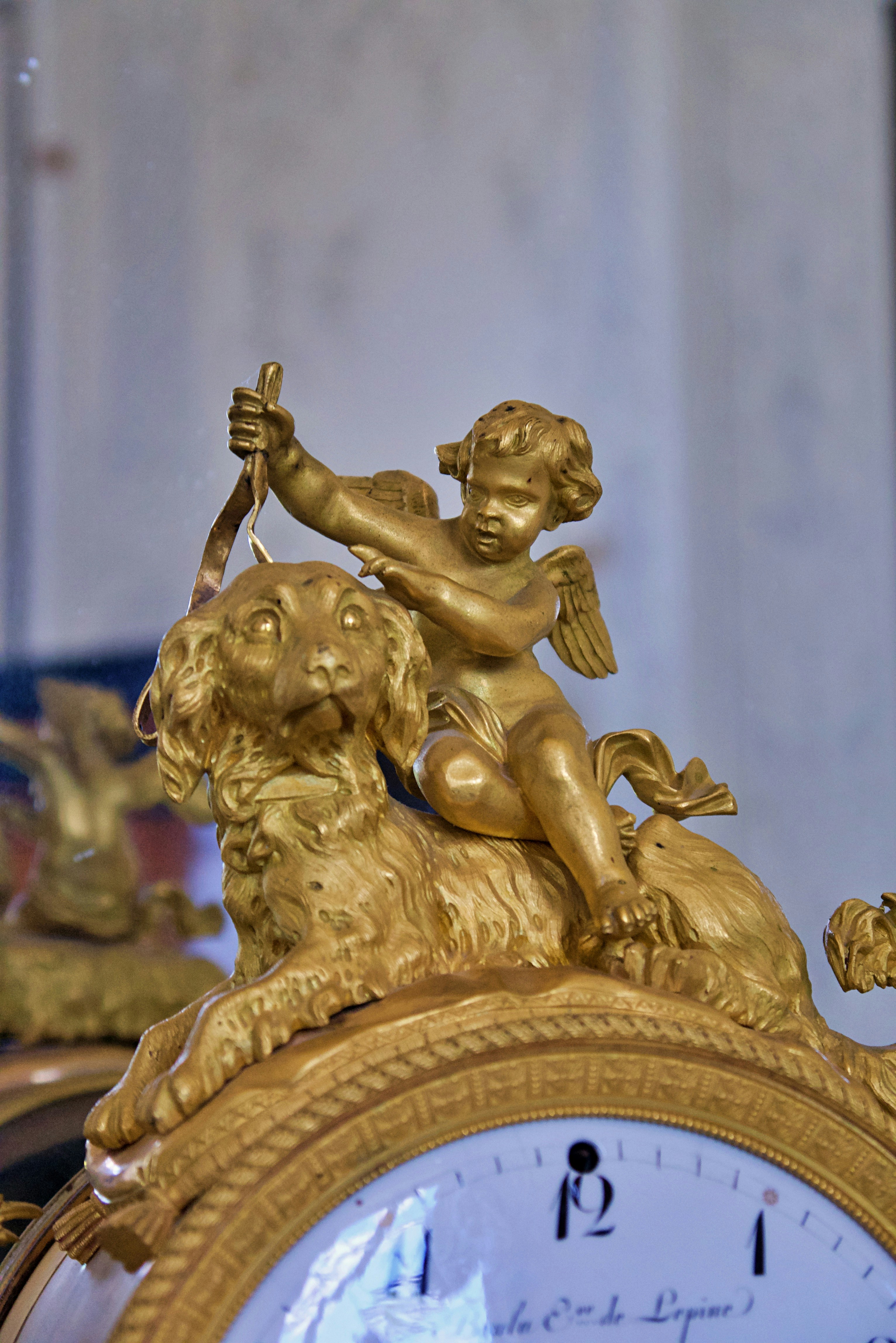 Querubim dourado montado em um cachorro em um relógio ornamentado.