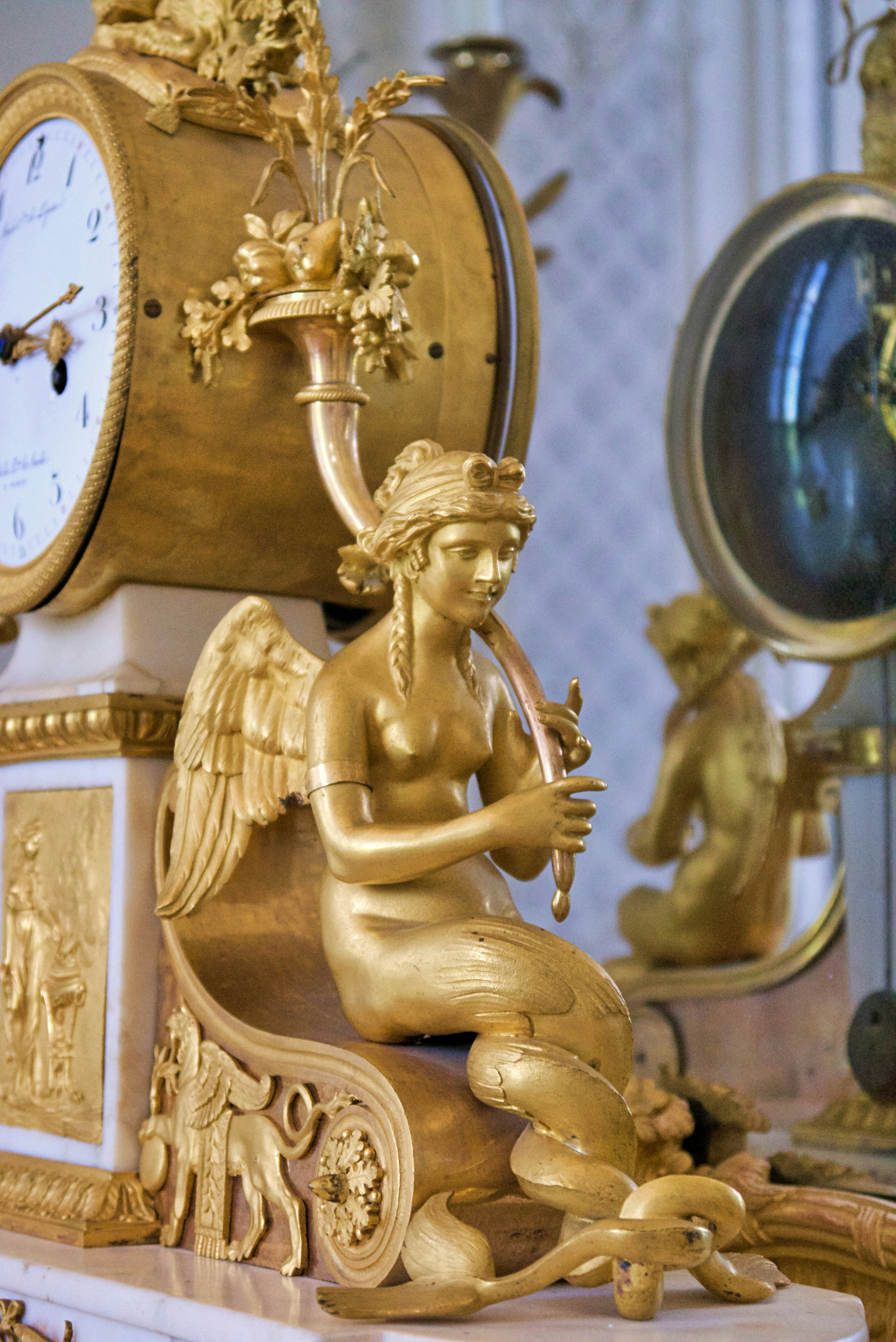 Relógio dourado ornamentado com figura angelical tocando flauta
