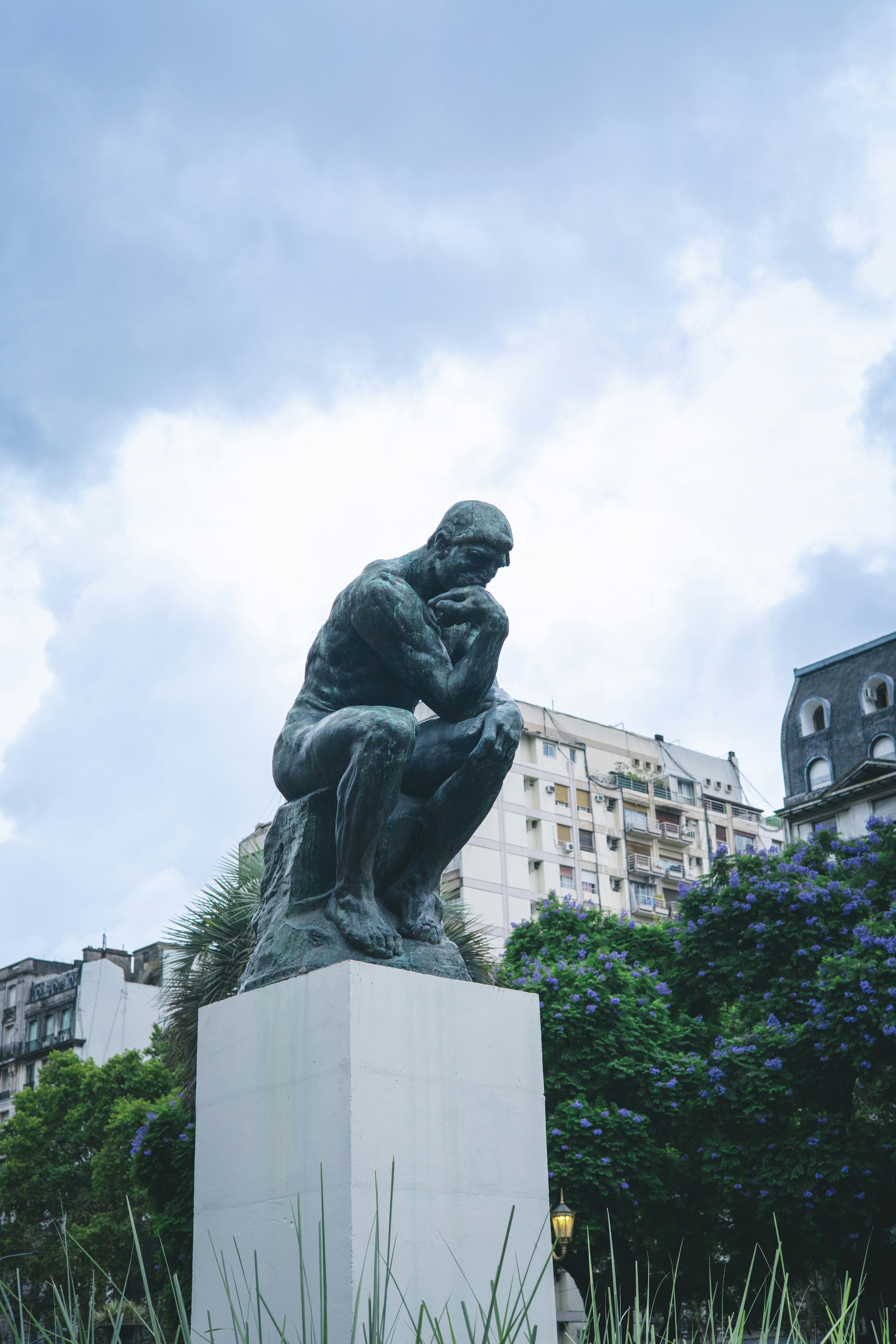 La estatua del pensador se sitúa sobre un pedestal al aire libre.