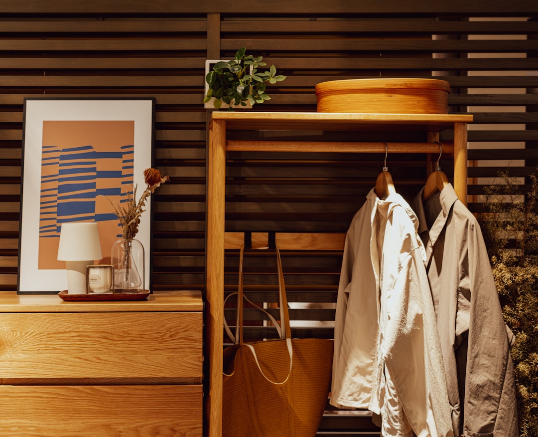 wooden dresser with lamp and art alongside a small open clothing rack with jackets