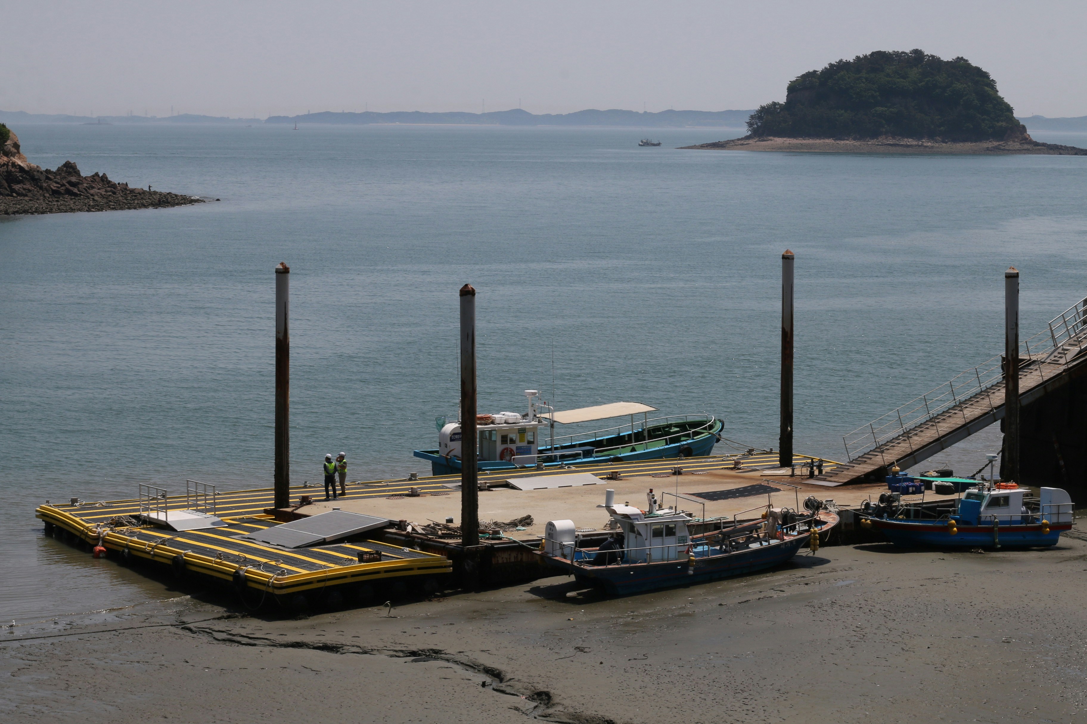 Boats docked at a floating pier by the sea.