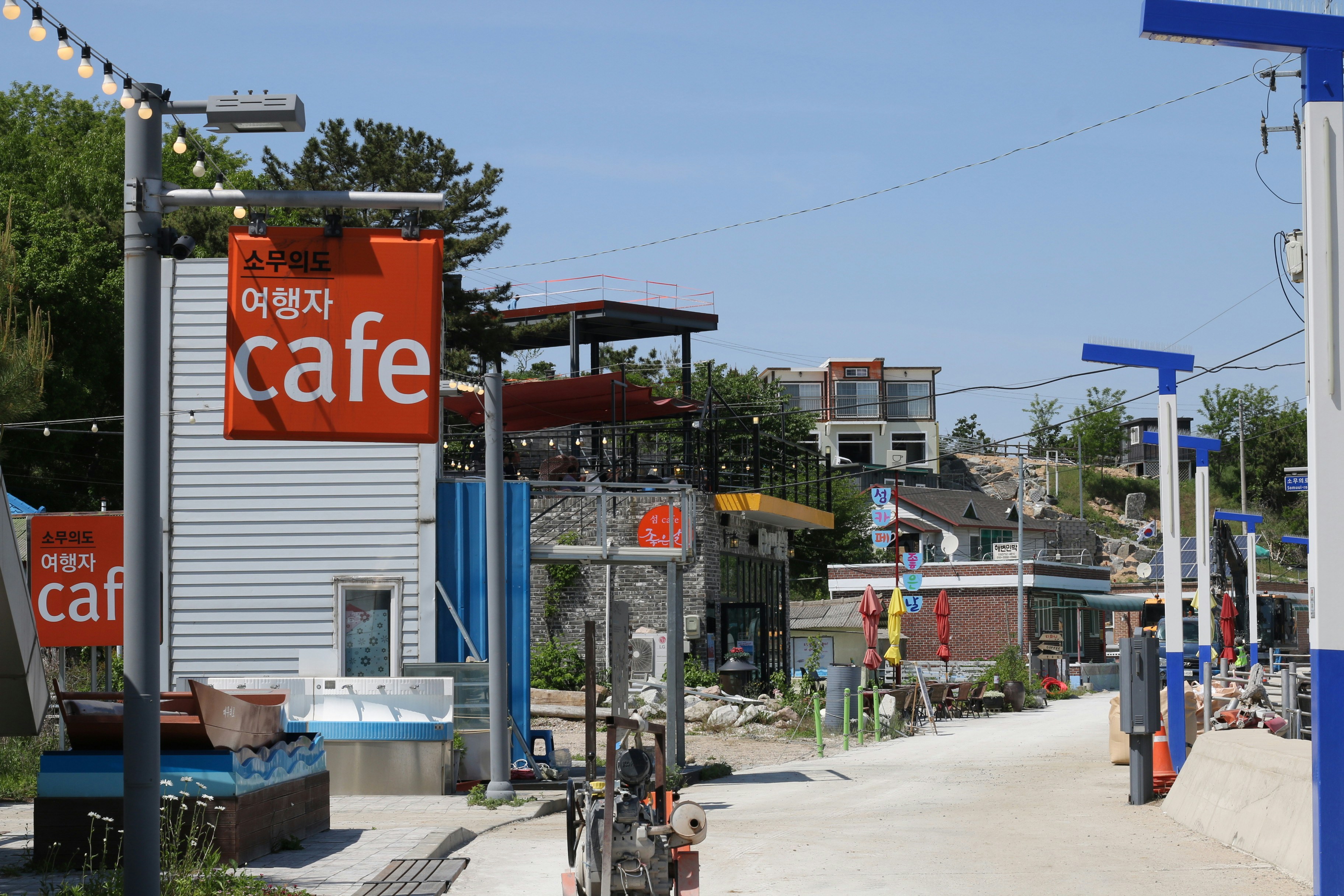 Orange cafe signs on a street with buildings.