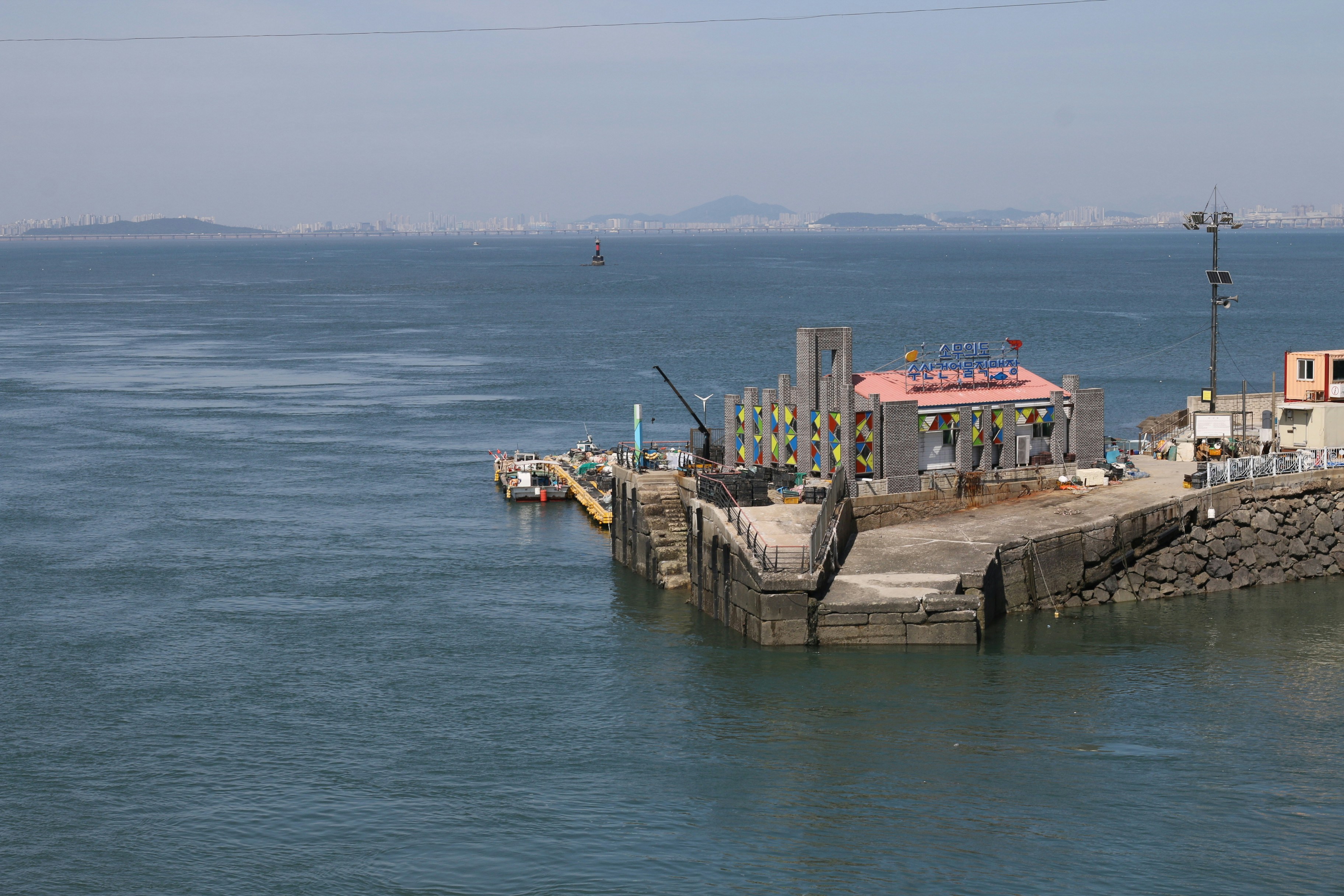 A pier with buildings and a crane on the water.
