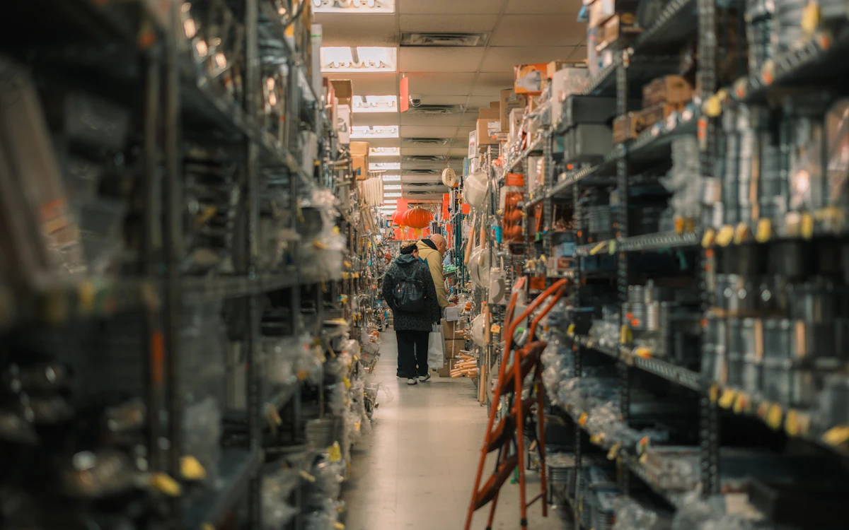 A person walking down a long aisle of stocked warehouse shelving