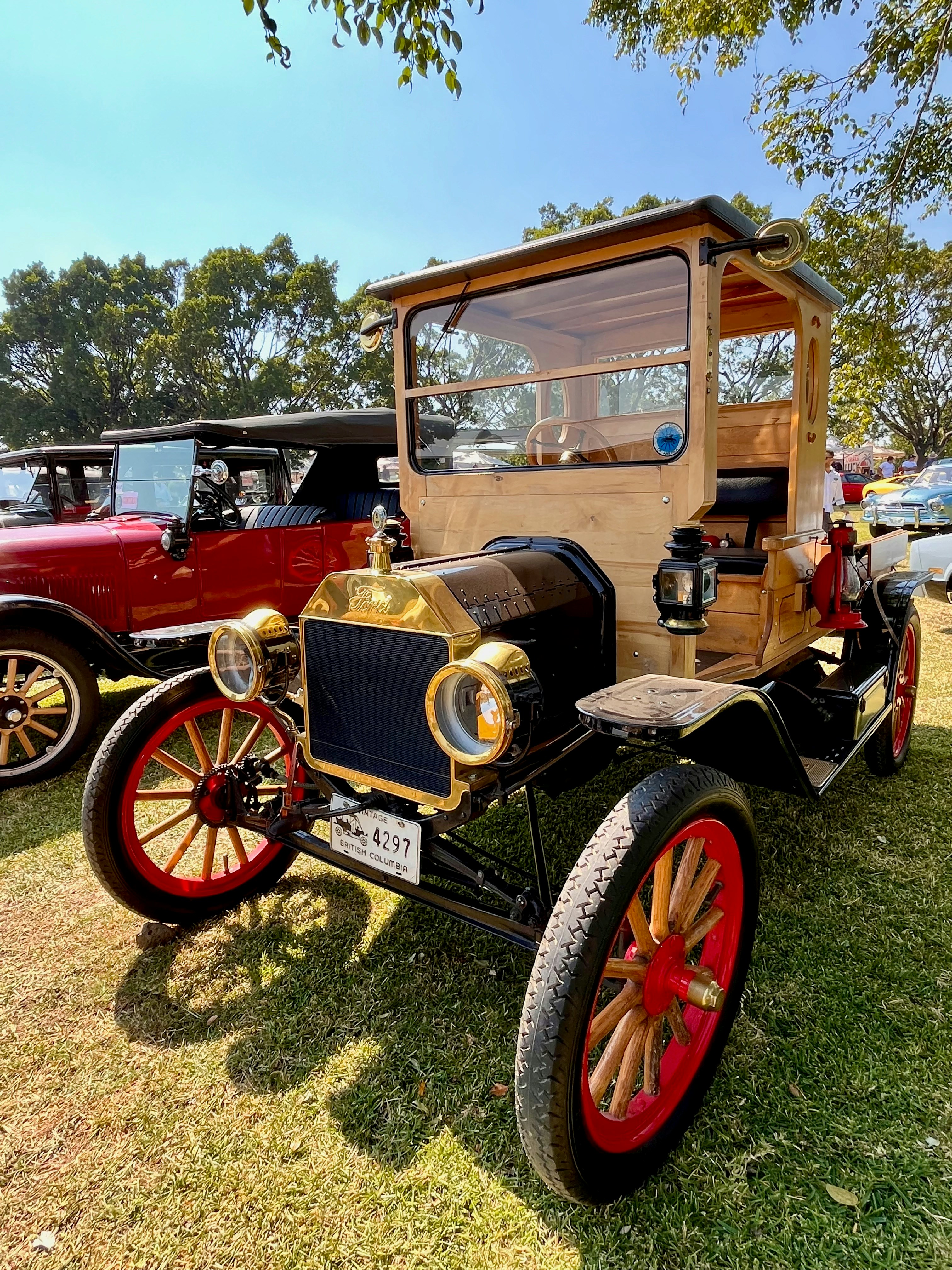 Voiture vintage en bois avec roues rouges sur l’herbe