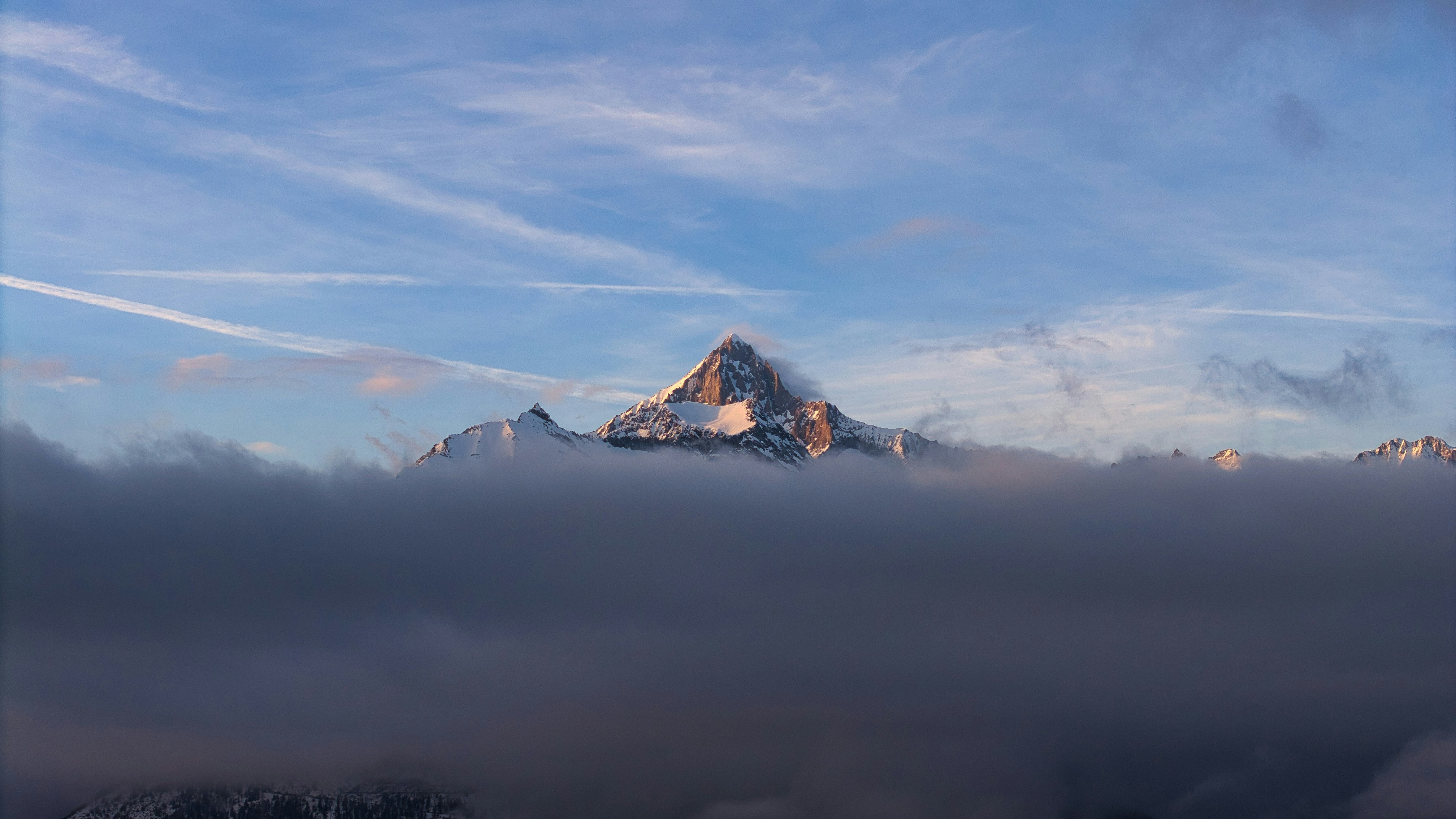 Snow-capped mountain peak emerging from clouds