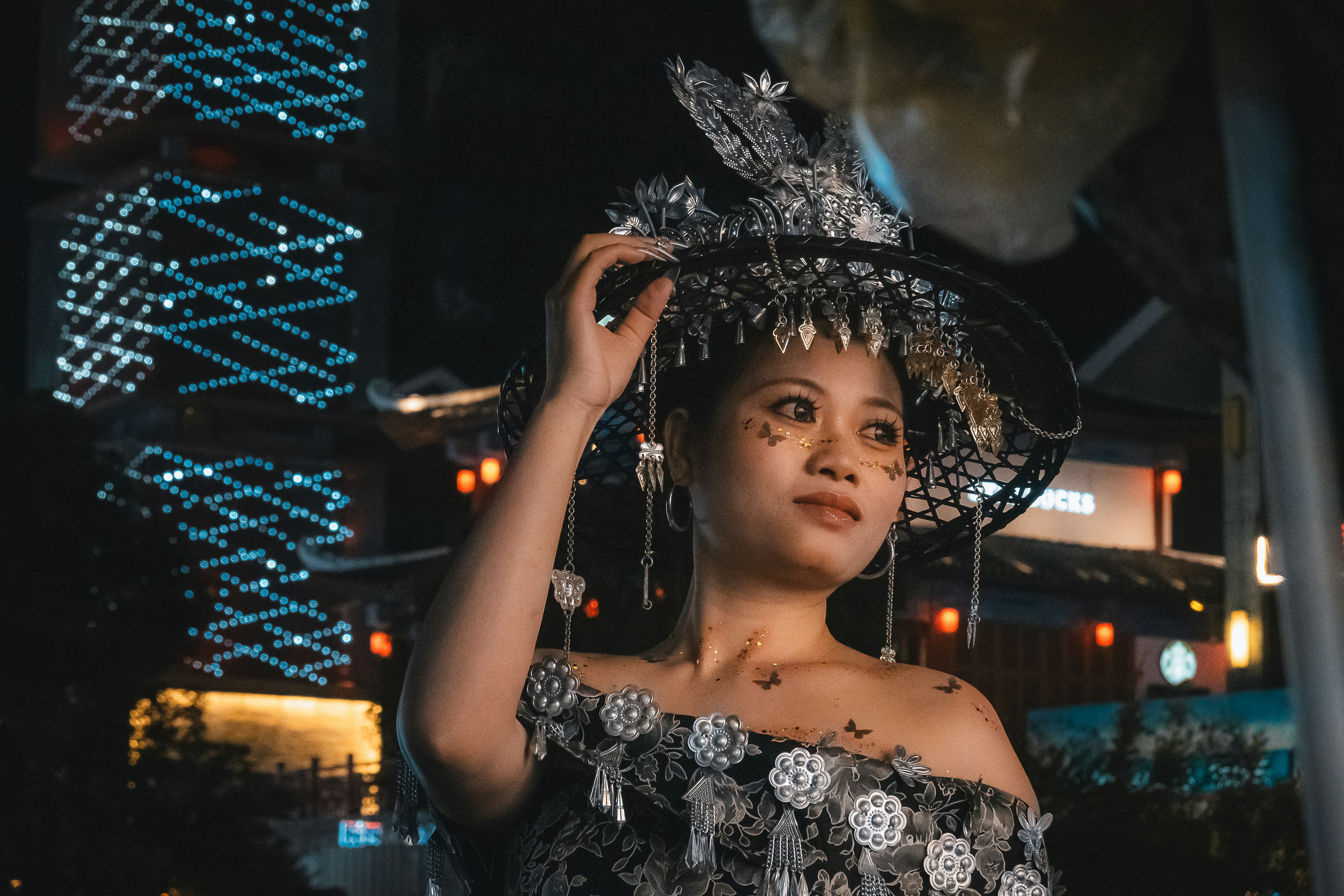 Mulher com chapéu e vestido ornamentados à noite