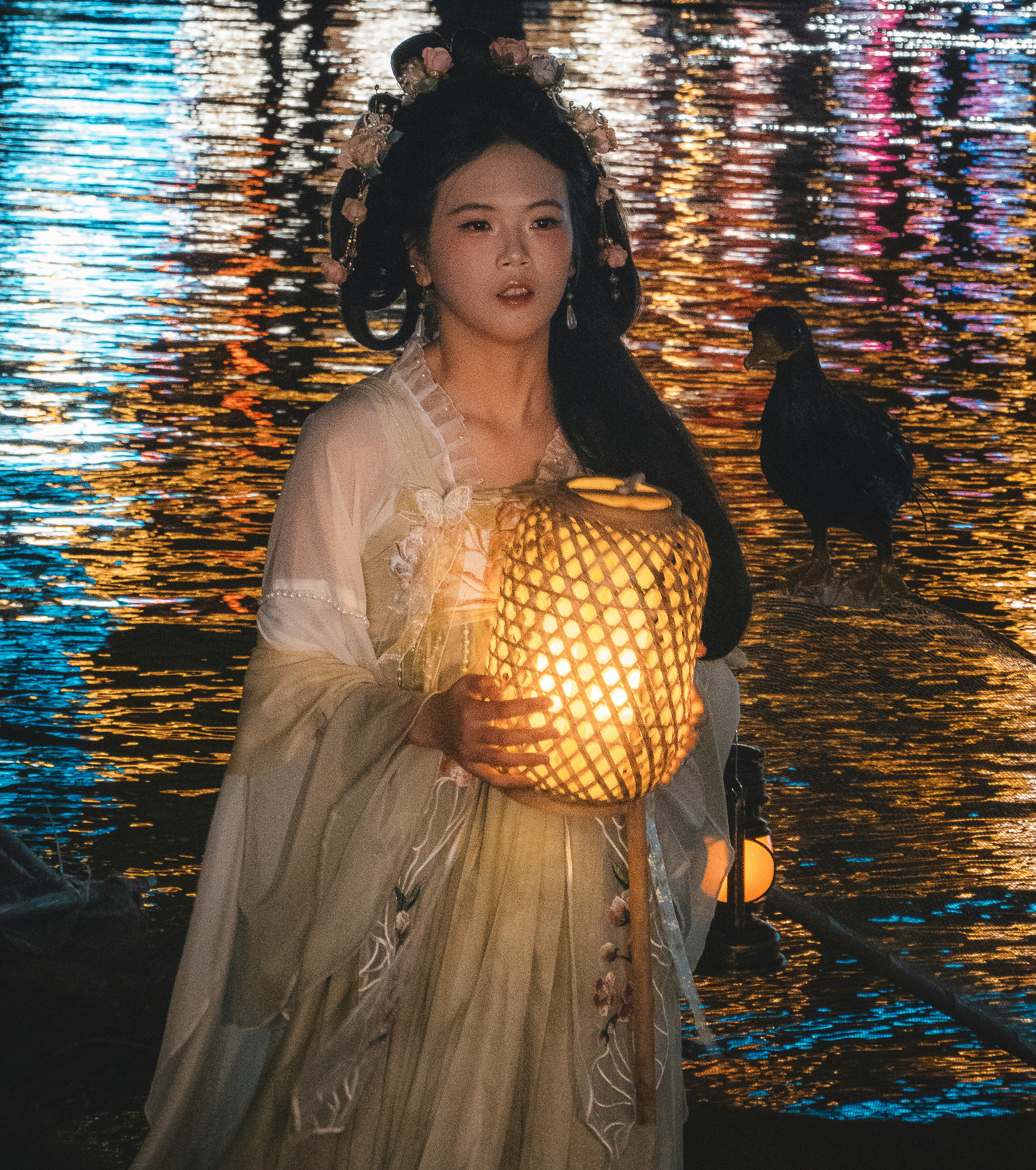 Mulher em traje tradicional segurando uma lanterna à beira da água