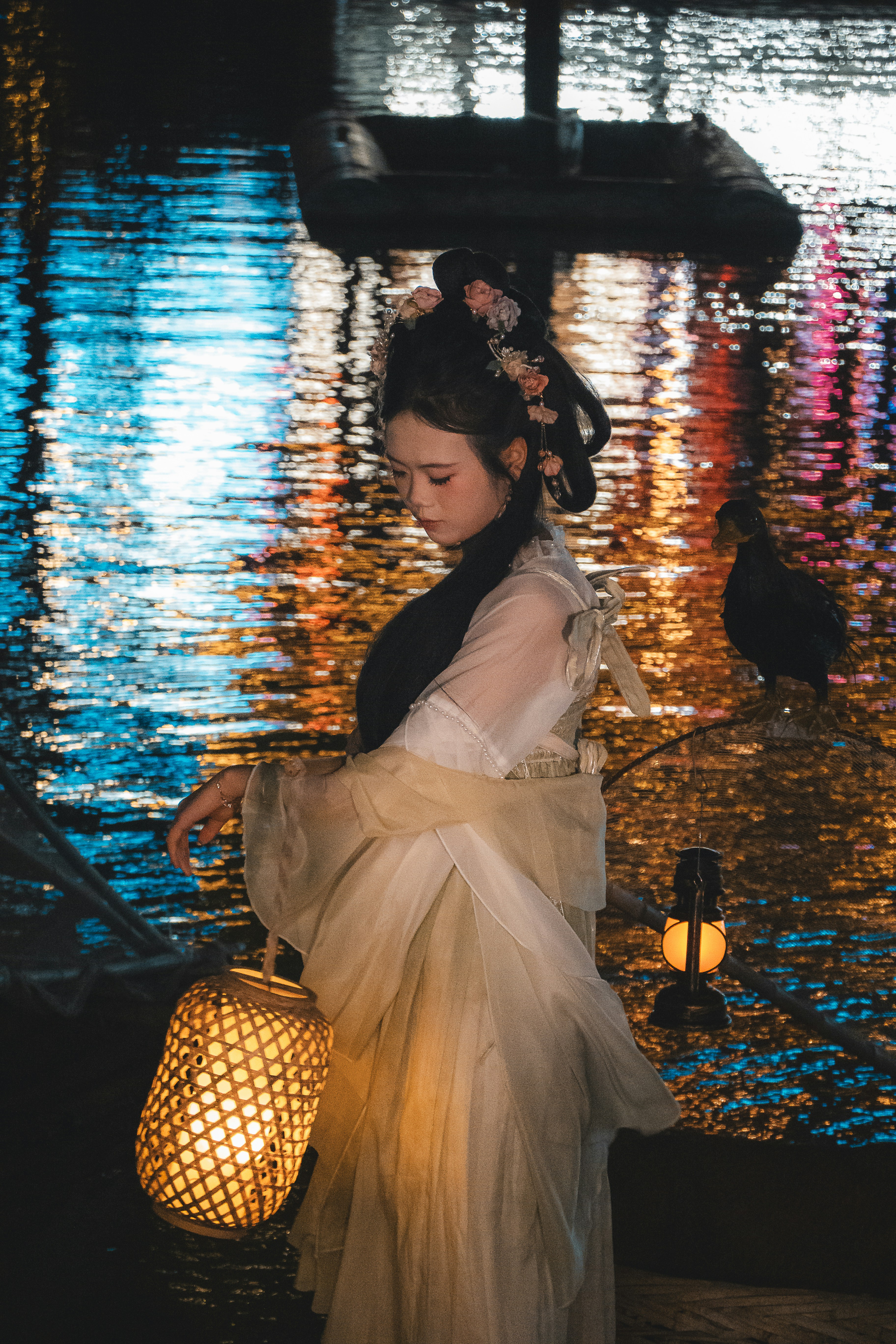Mulher em traje tradicional segurando uma lanterna à beira da água