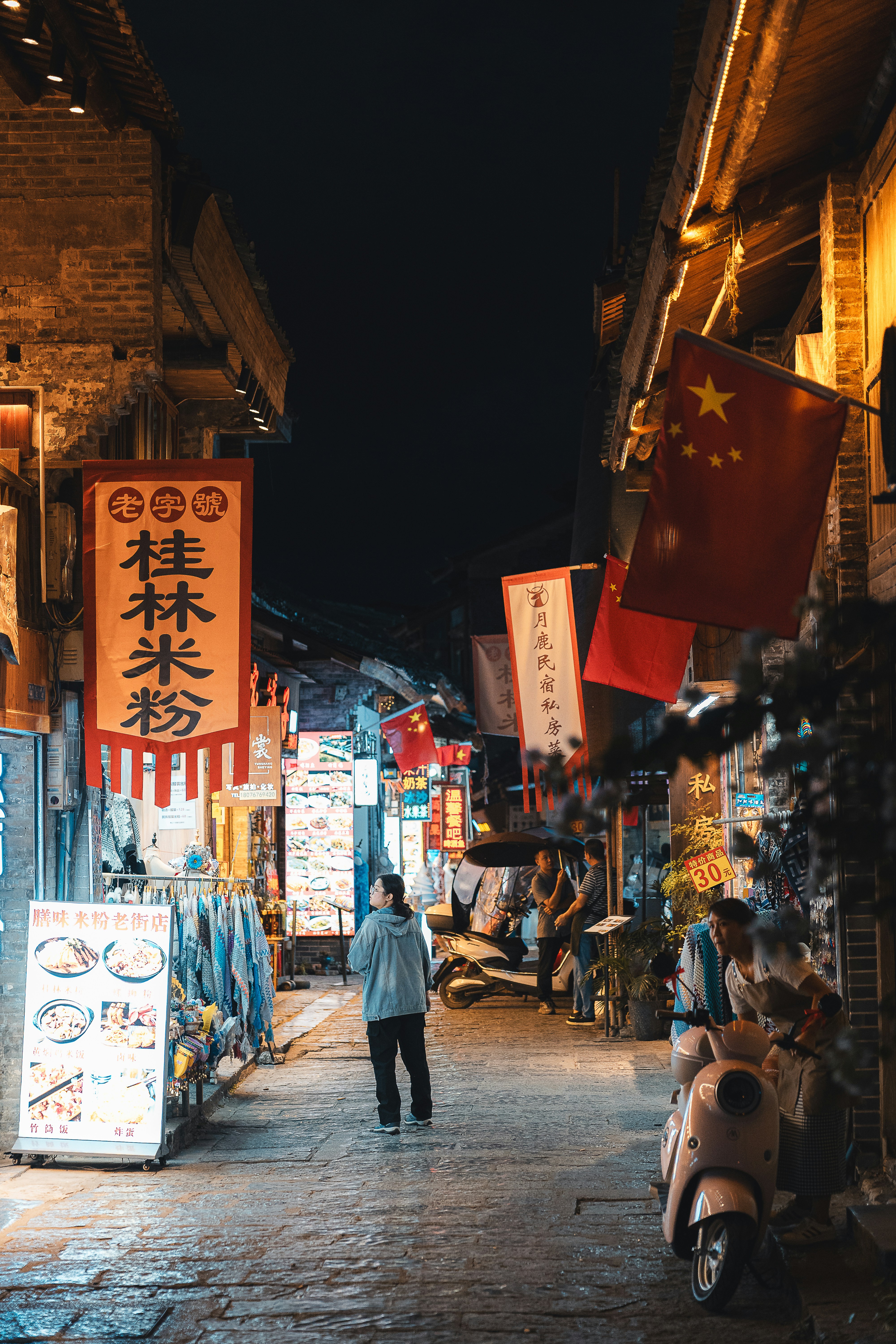 Uma rua estreita em uma cidade chinesa à noite.