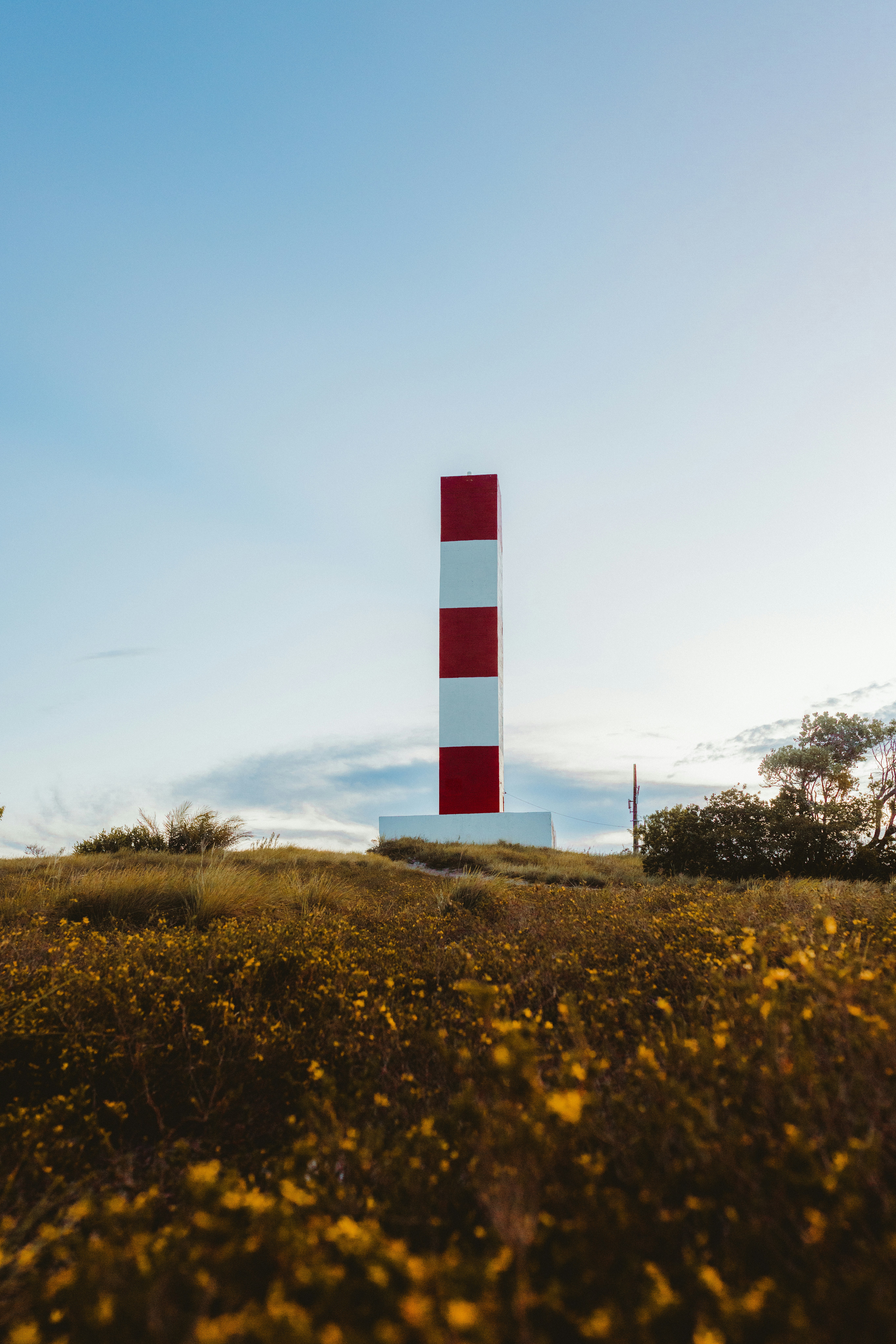 Menara bergaris merah dan putih di atas bukit berumput