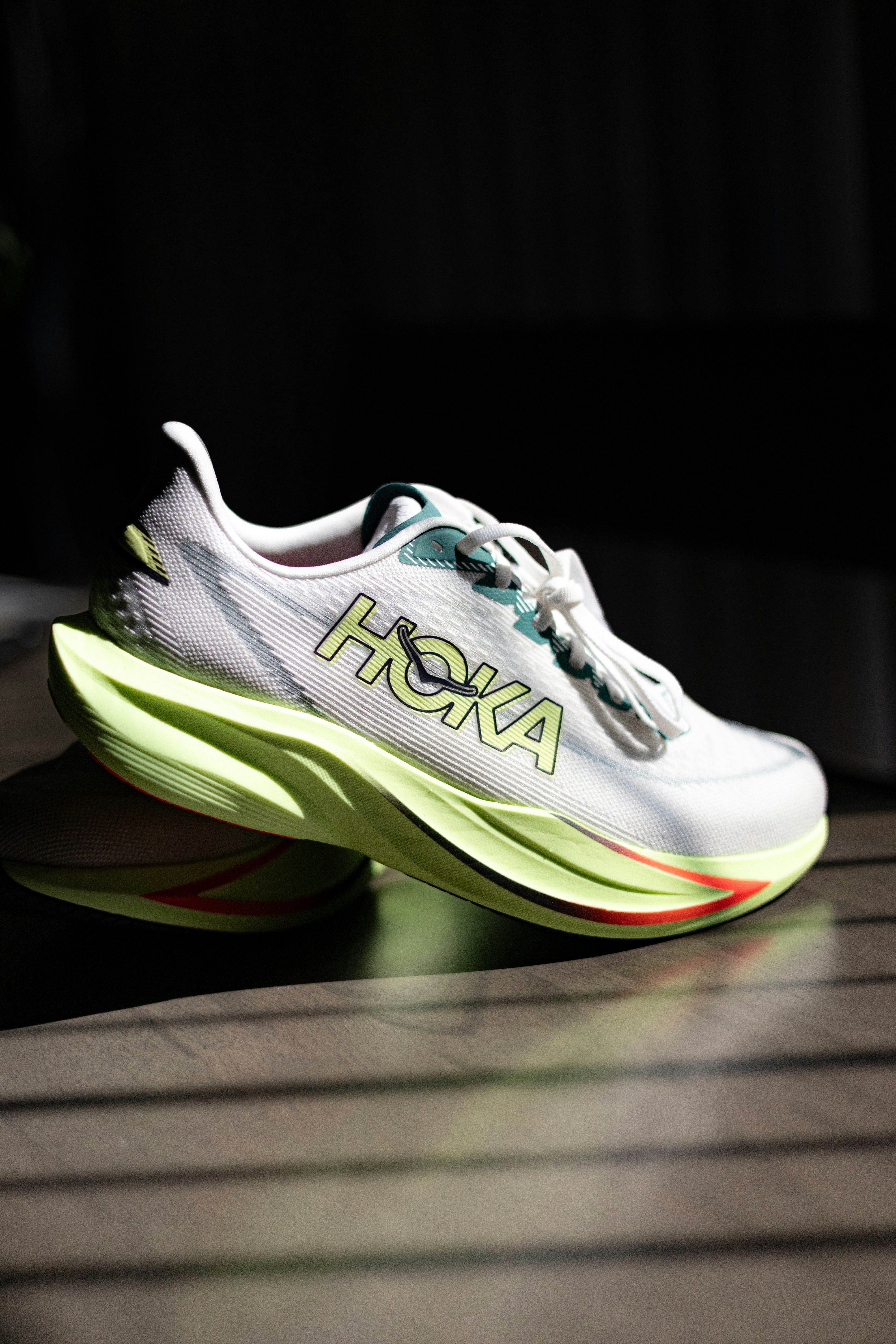 White hoka running shoes with lime green accents.