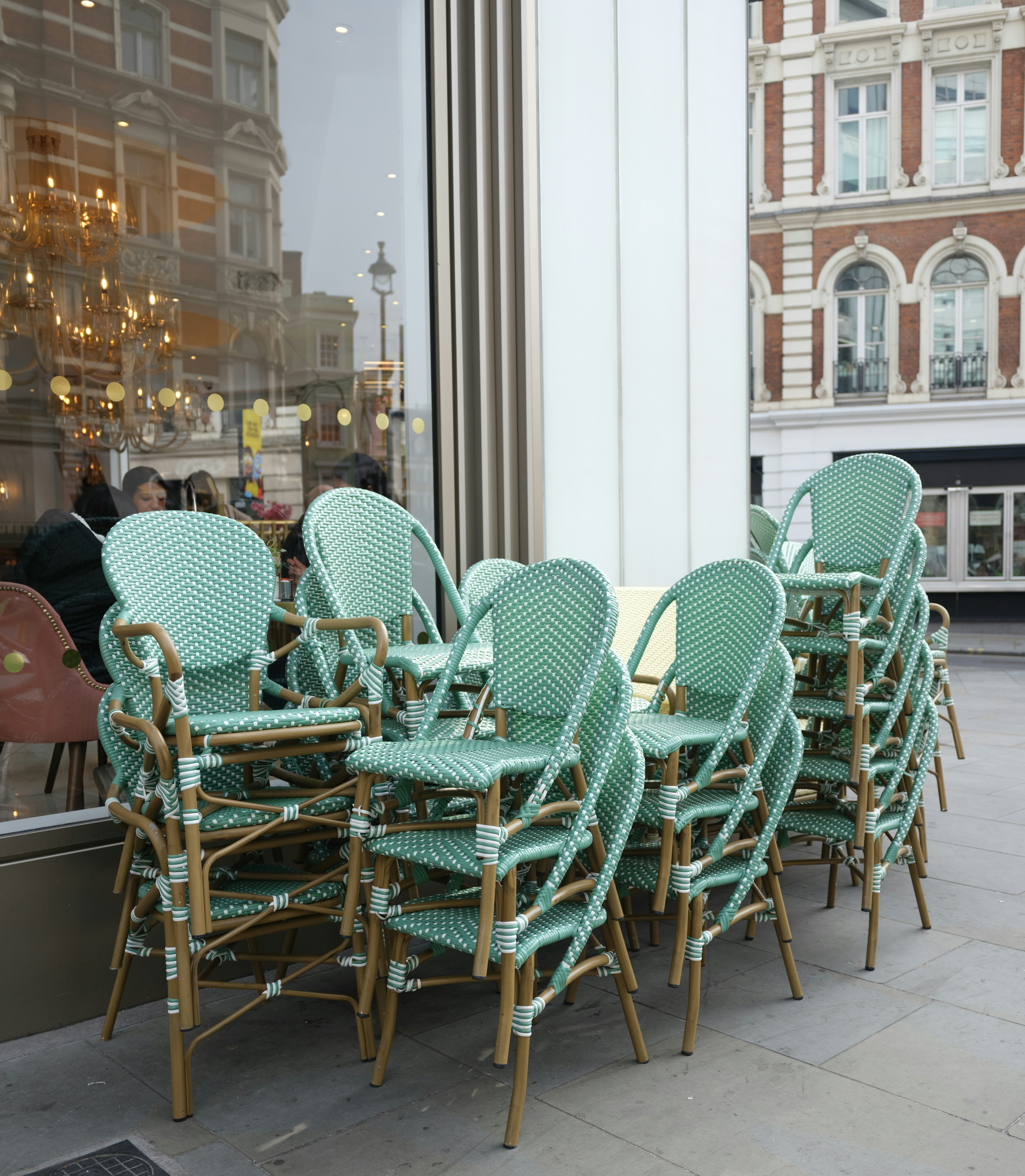 Stacked outdoor cafe chairs on a sidewalk.