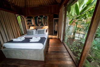 Cozy bedroom with large window overlooking lush greenery