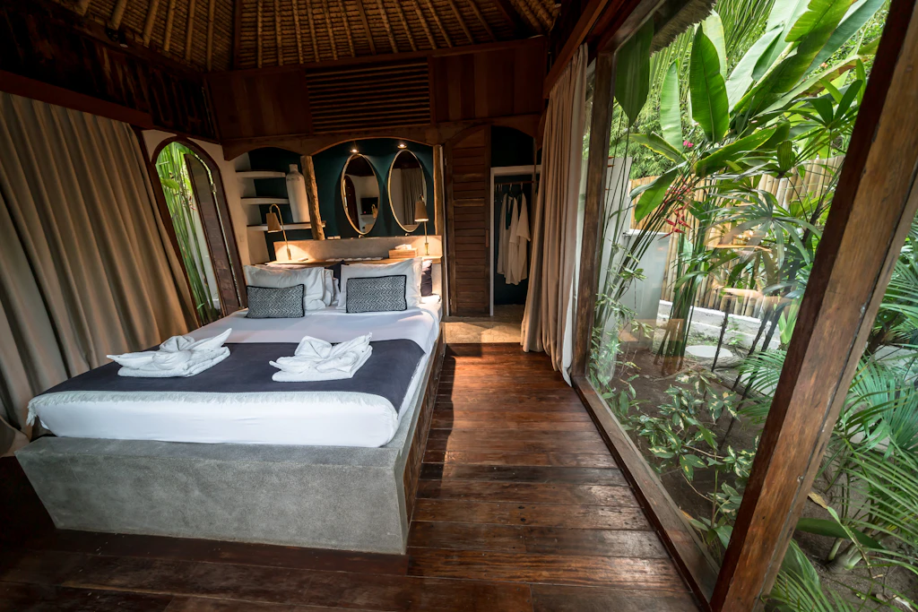 Timber bedroom with large windows onto lush greenery