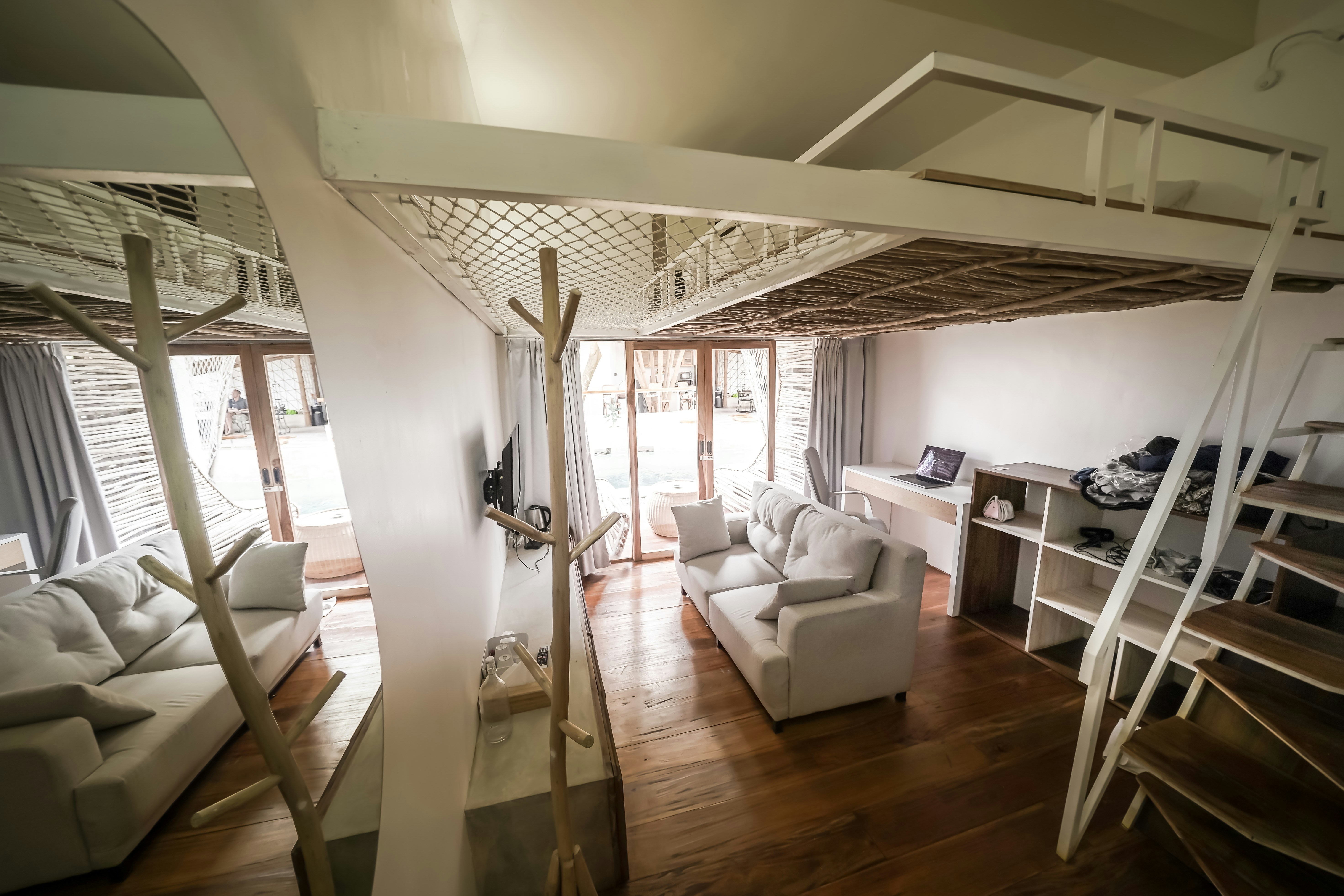 Cozy living room with white sofas and loft bed.