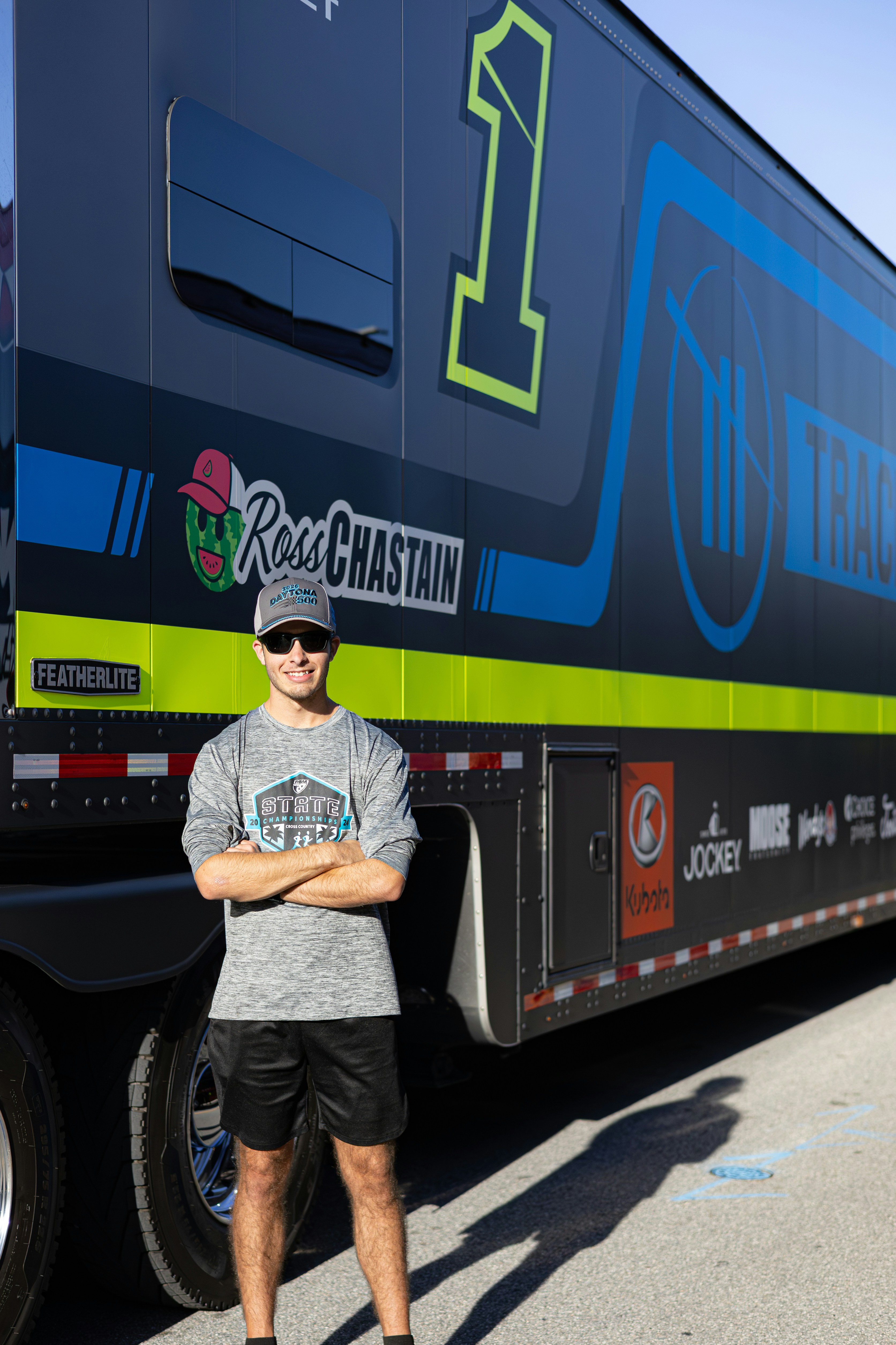 Man in cap and t-shirt stands by race car trailer