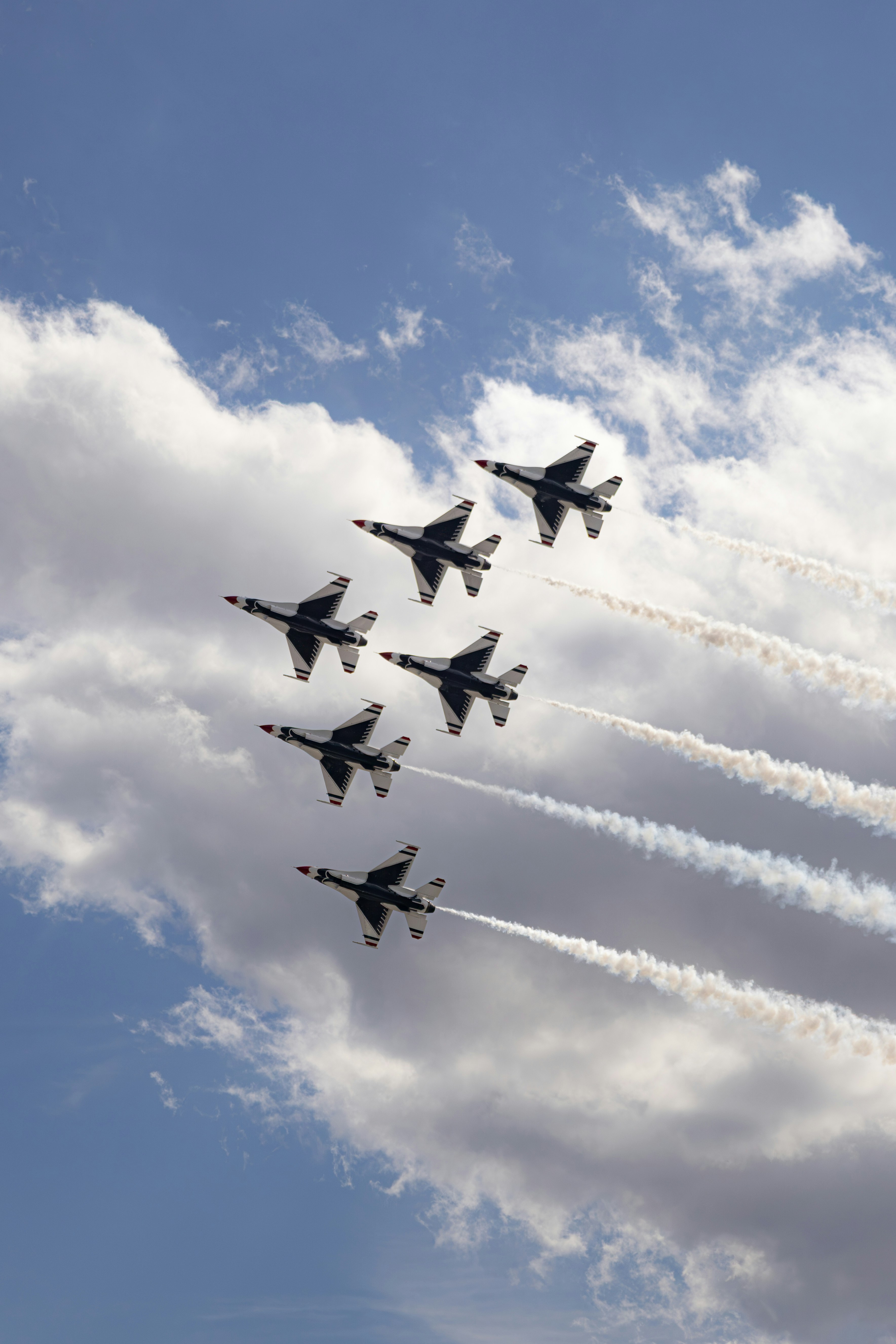 Sechs Kampfjets fliegen in Formation mit Rauchspuren.