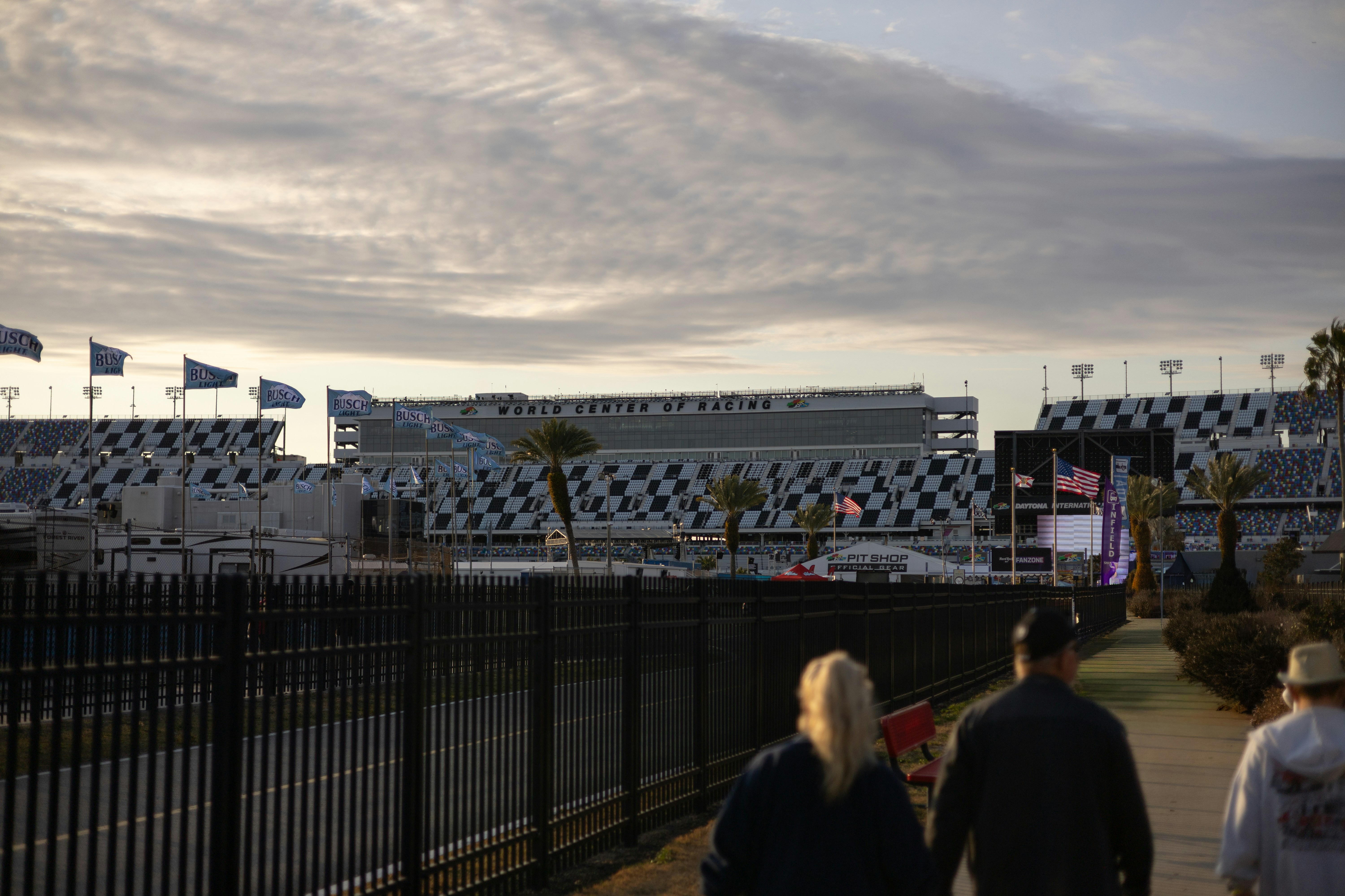 People walk towards a grandstand at a racetrack.