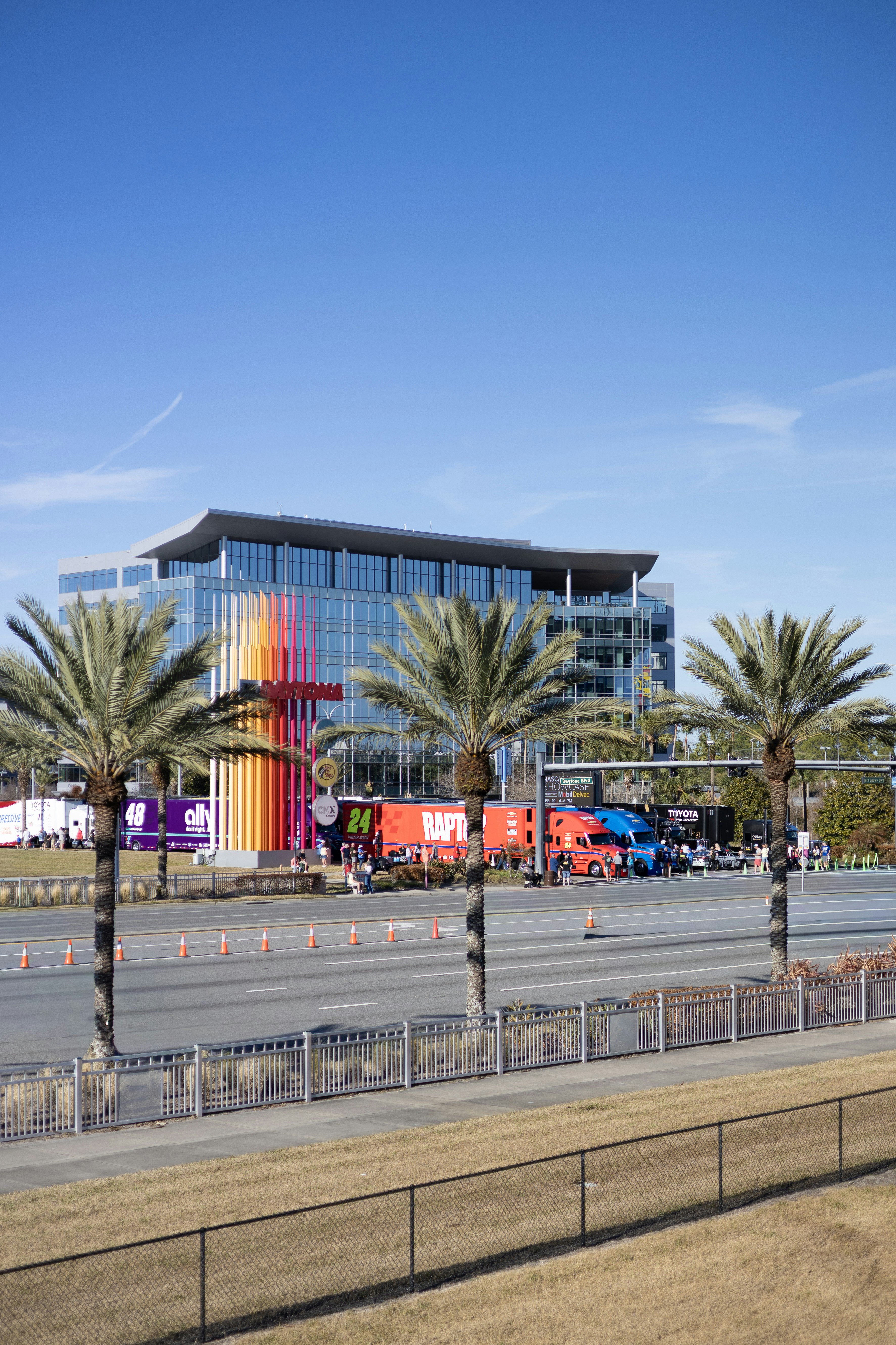 Modern glass building with colorful art installation and palm trees