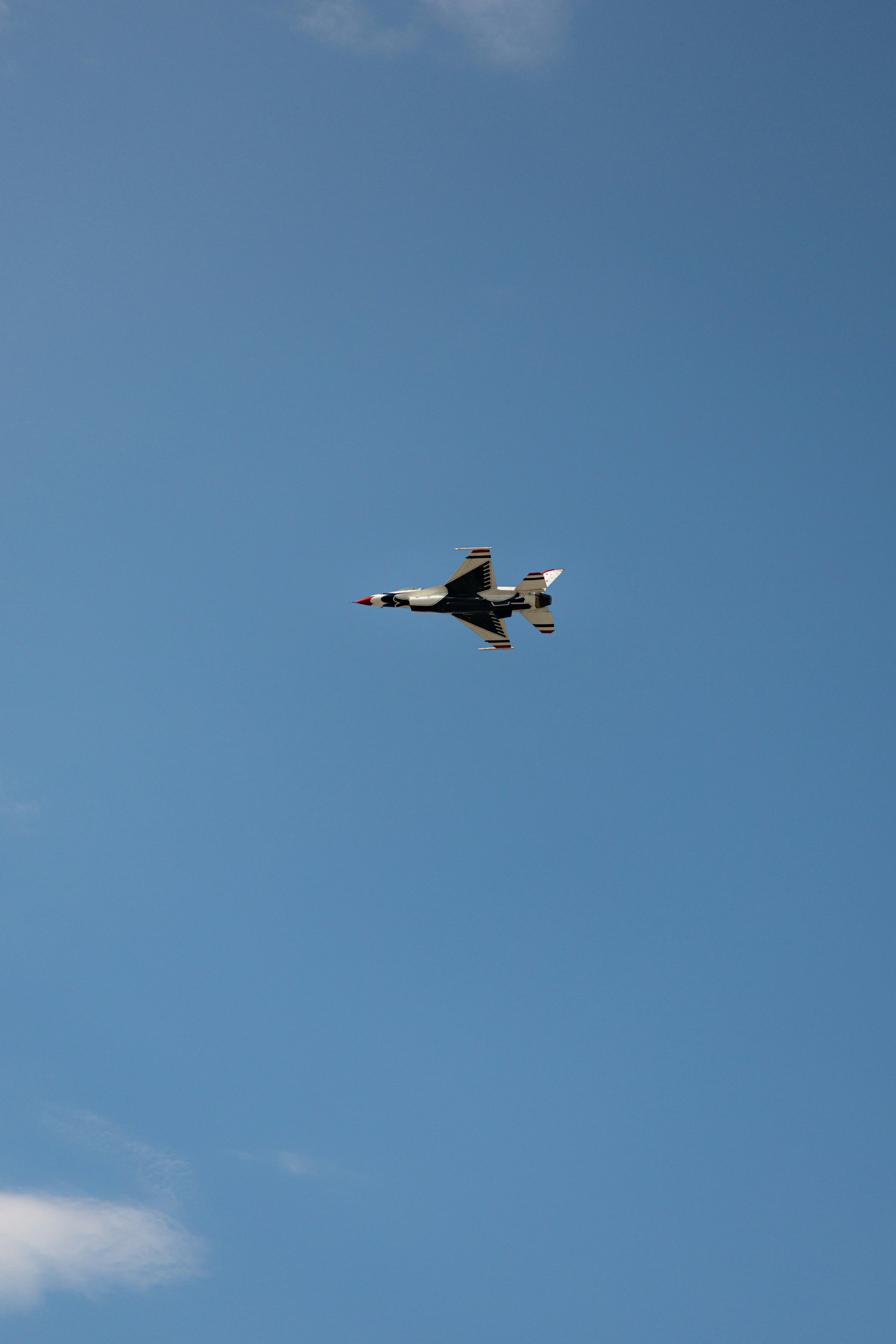 A fighter jet flies high in the clear blue sky