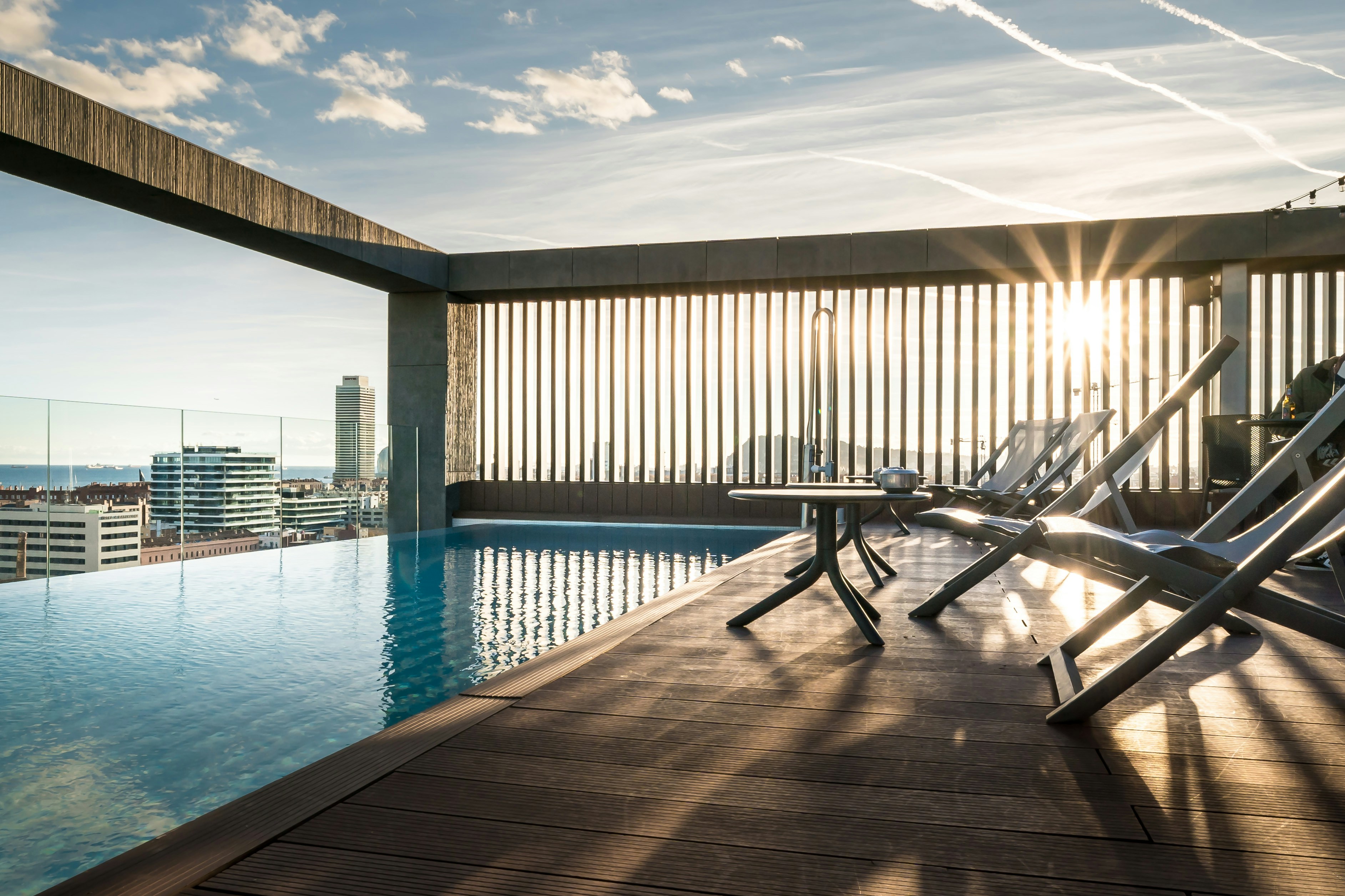 Rooftop infinity pool with lounge chairs and city view.