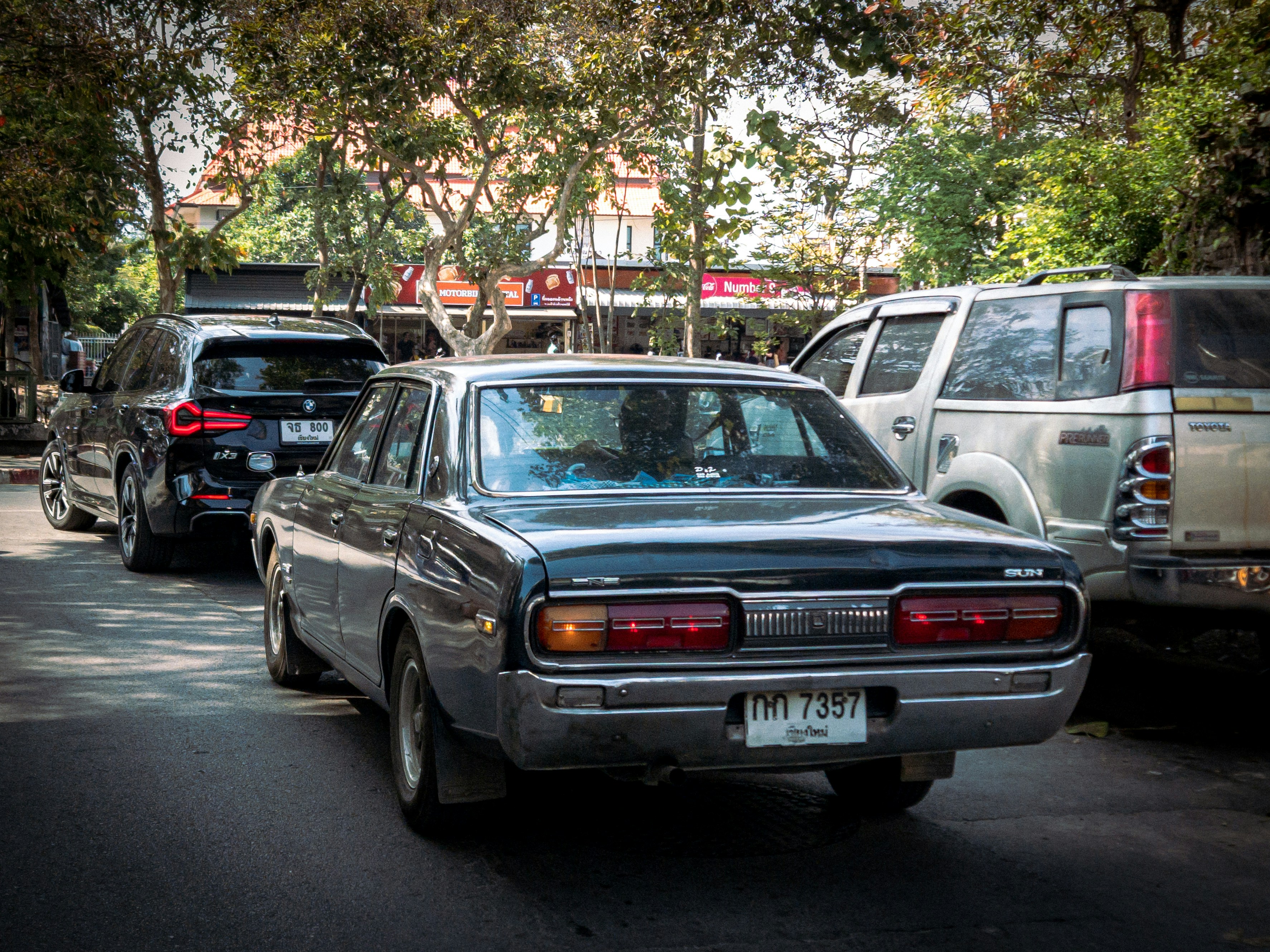 An older sedan parked next to a new luxury SUV