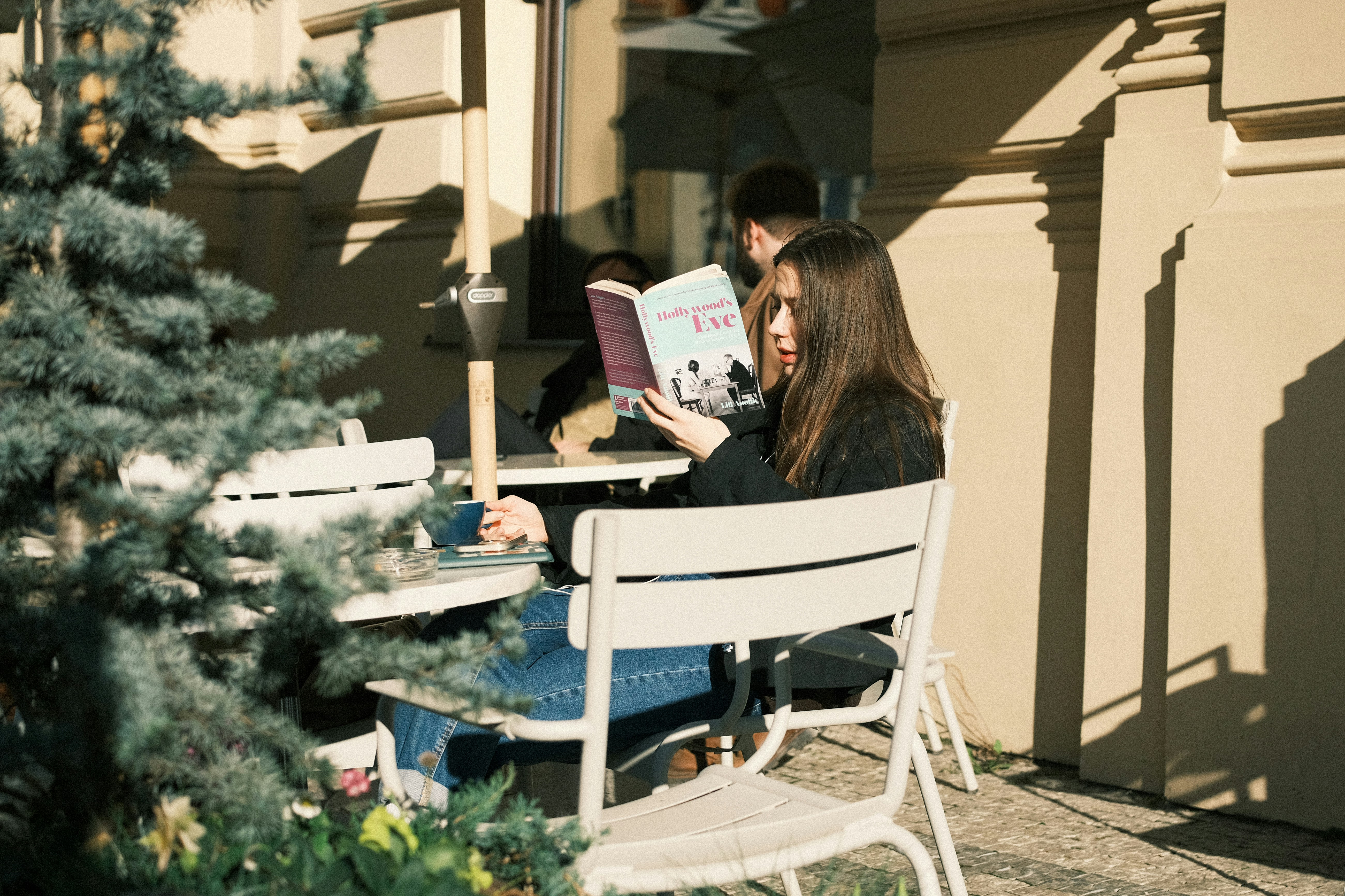Giovane donna che legge un libro in un caffè all'aperto.