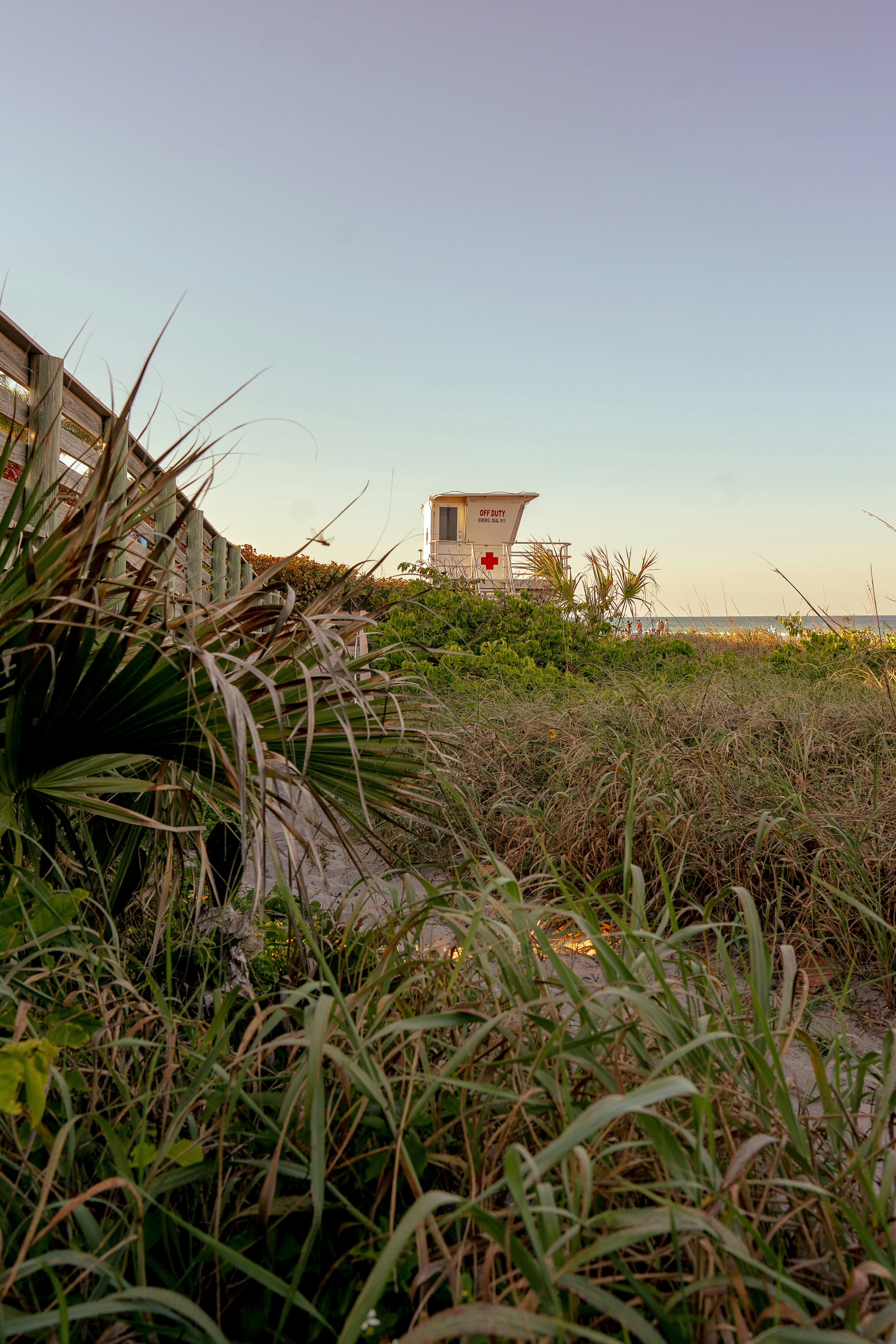 Lifeguard tower behind beach grass and wooden walkway