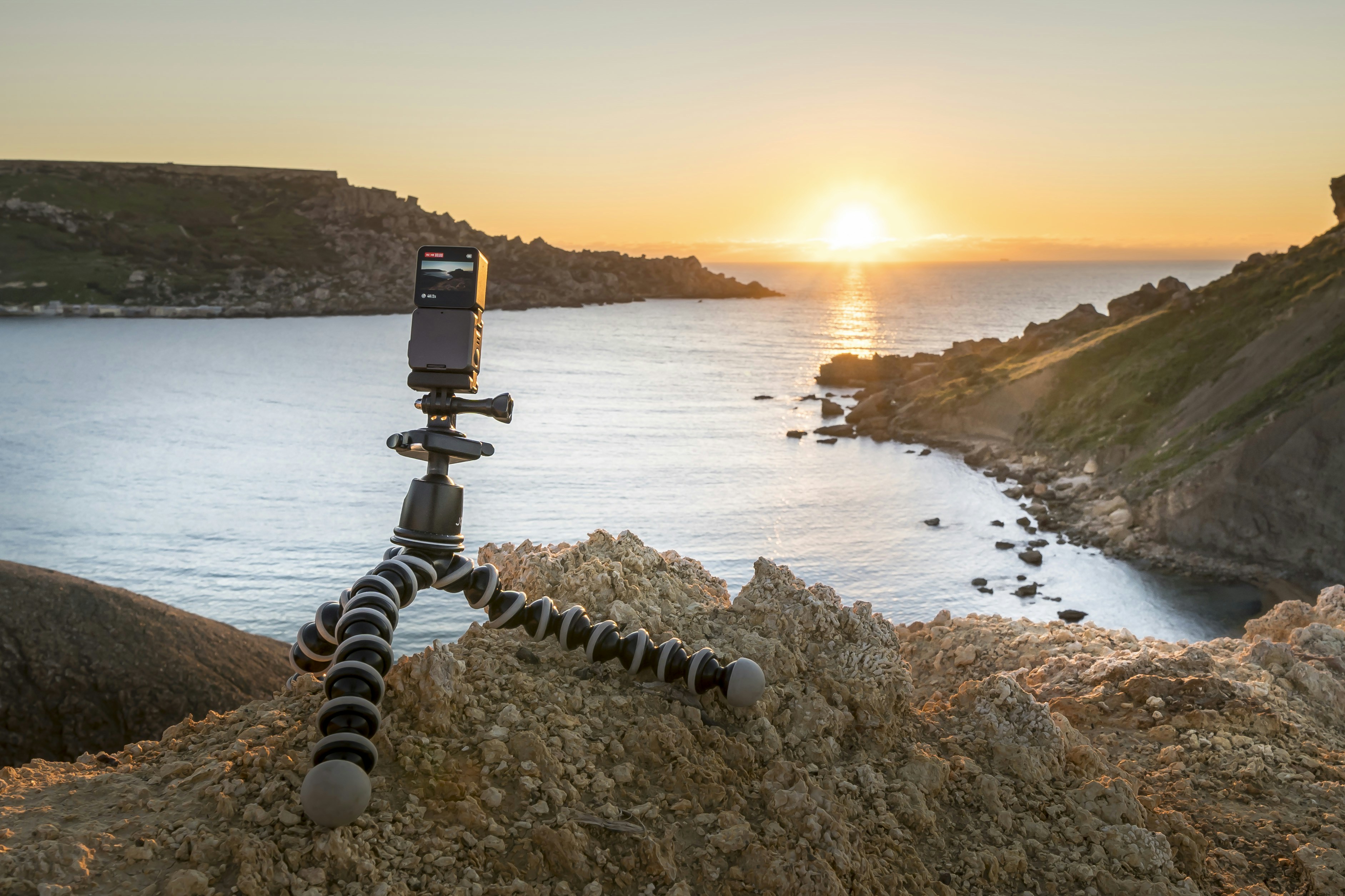 Camera on tripod overlooking ocean at sunset