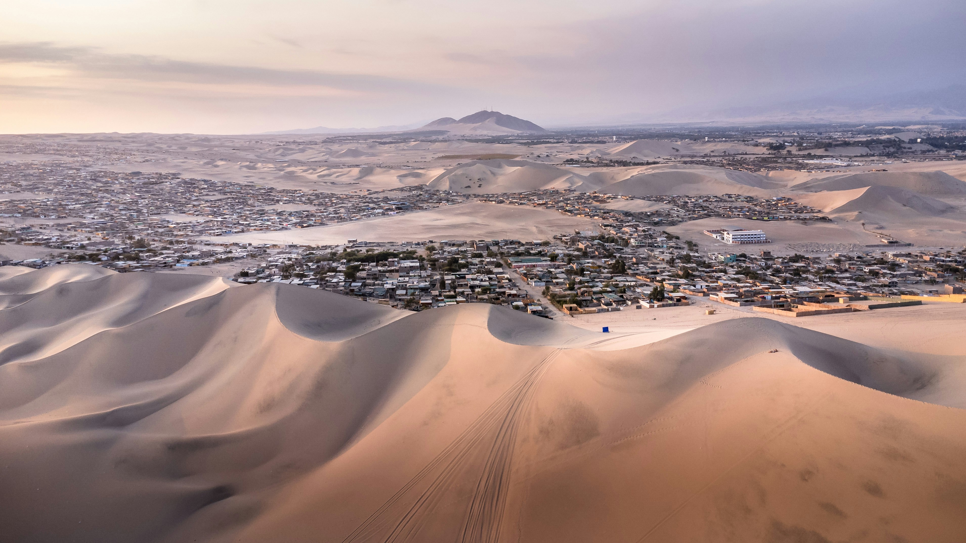 Vast desert landscape with rolling sand dunes and a town.